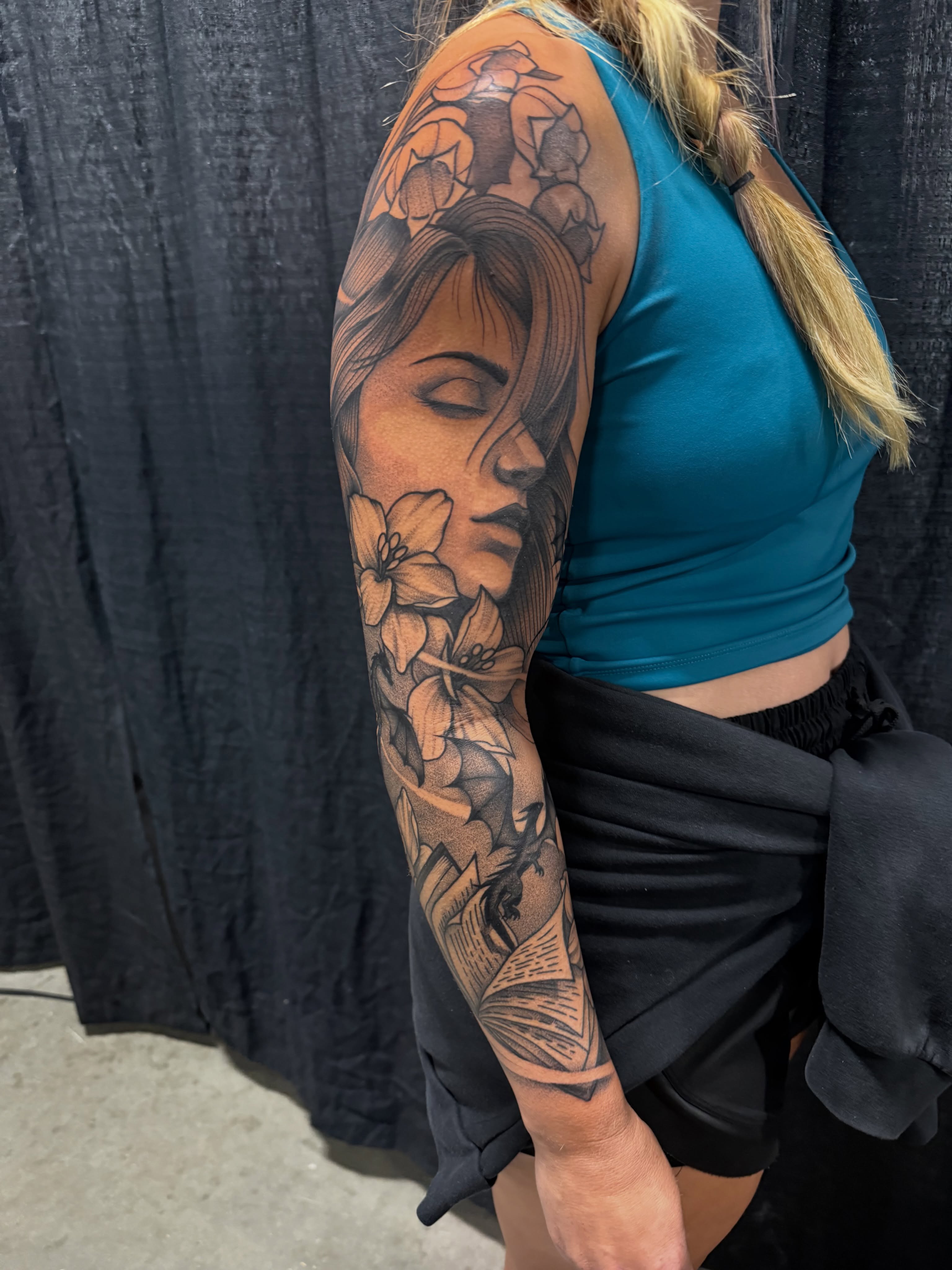 Woman with flowers realism tattoo on the upper arm by Justin Hay