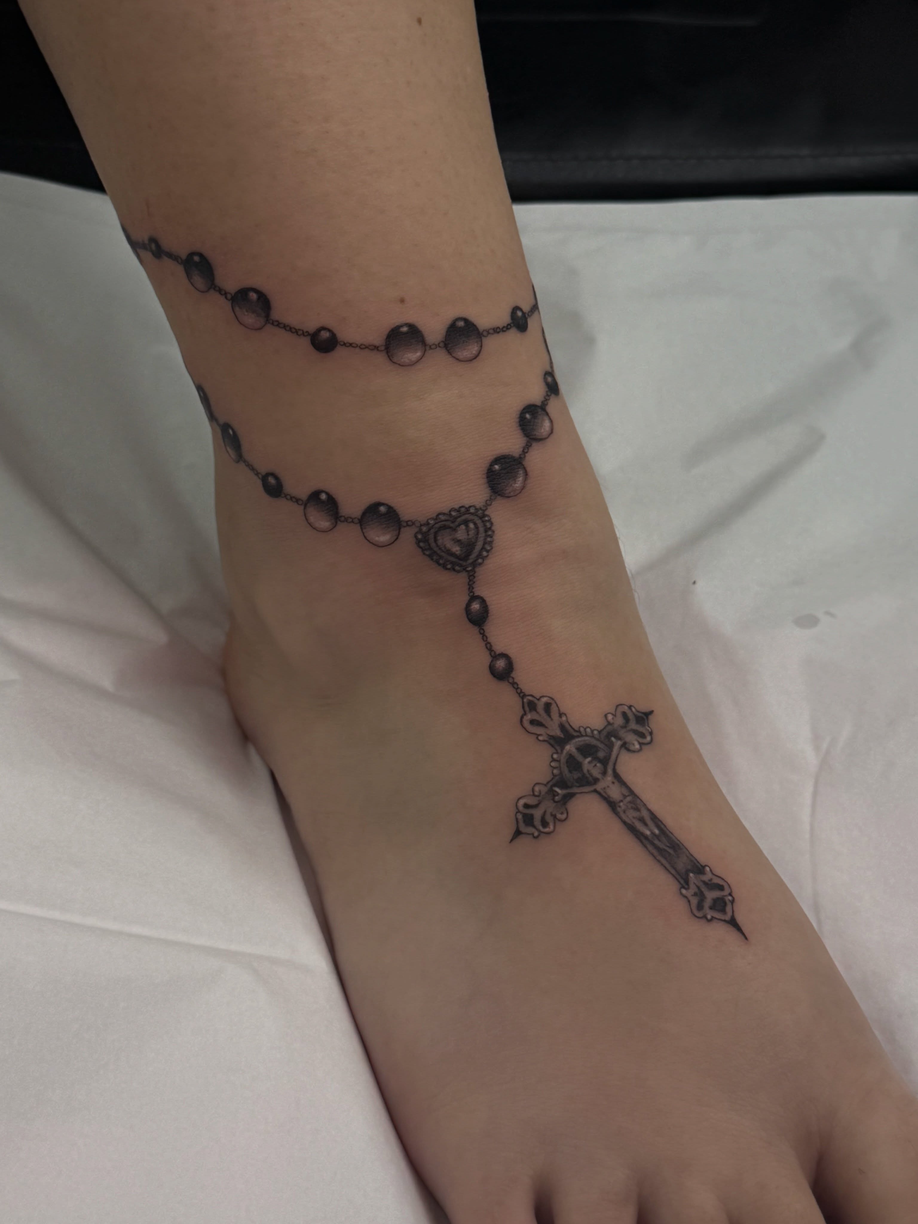 Rosary black and grey tattoo on the foot by Halle Cooper
