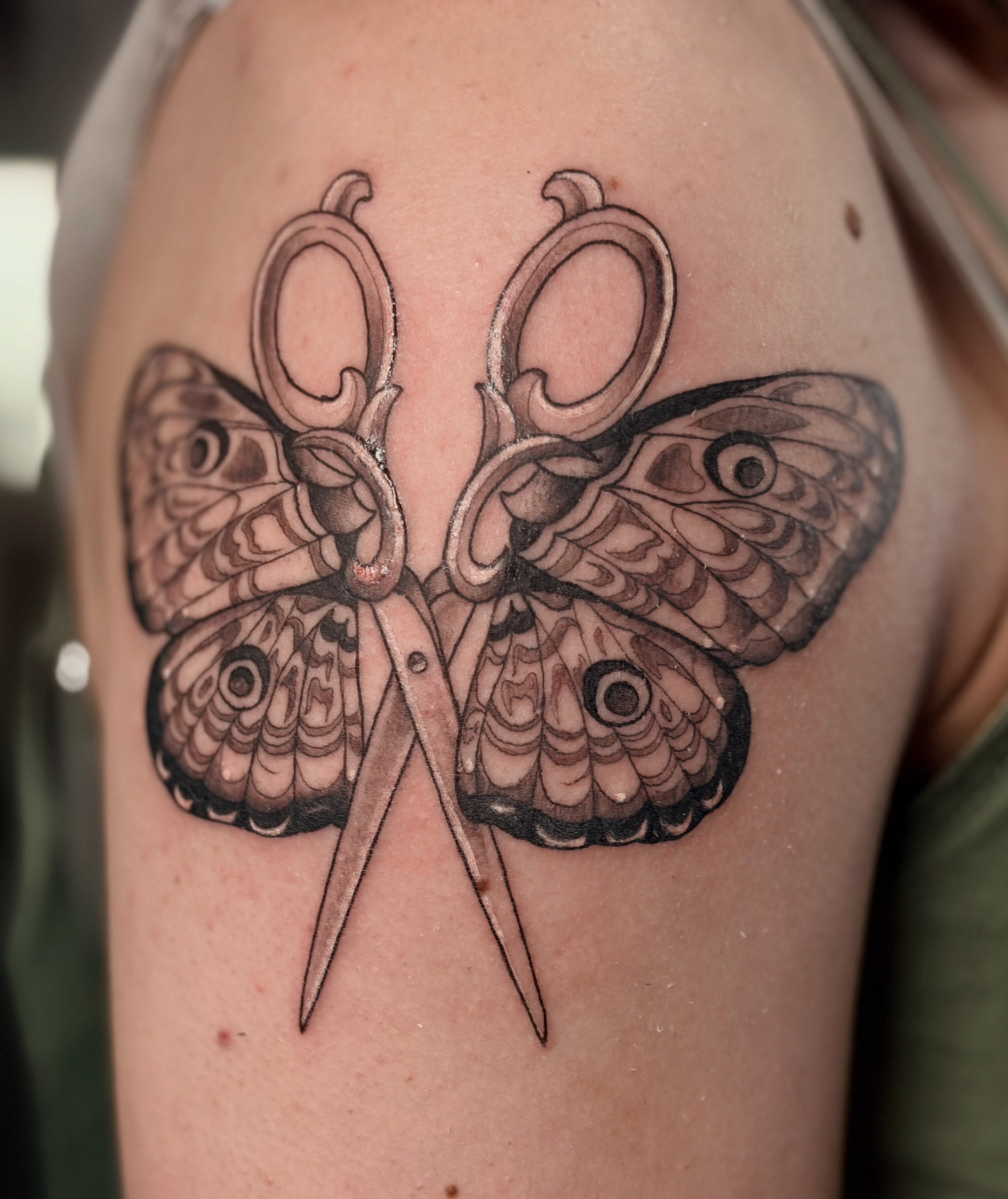 Scissors and butterfly black and grey tattoo on the shoulder by Audrey Luther