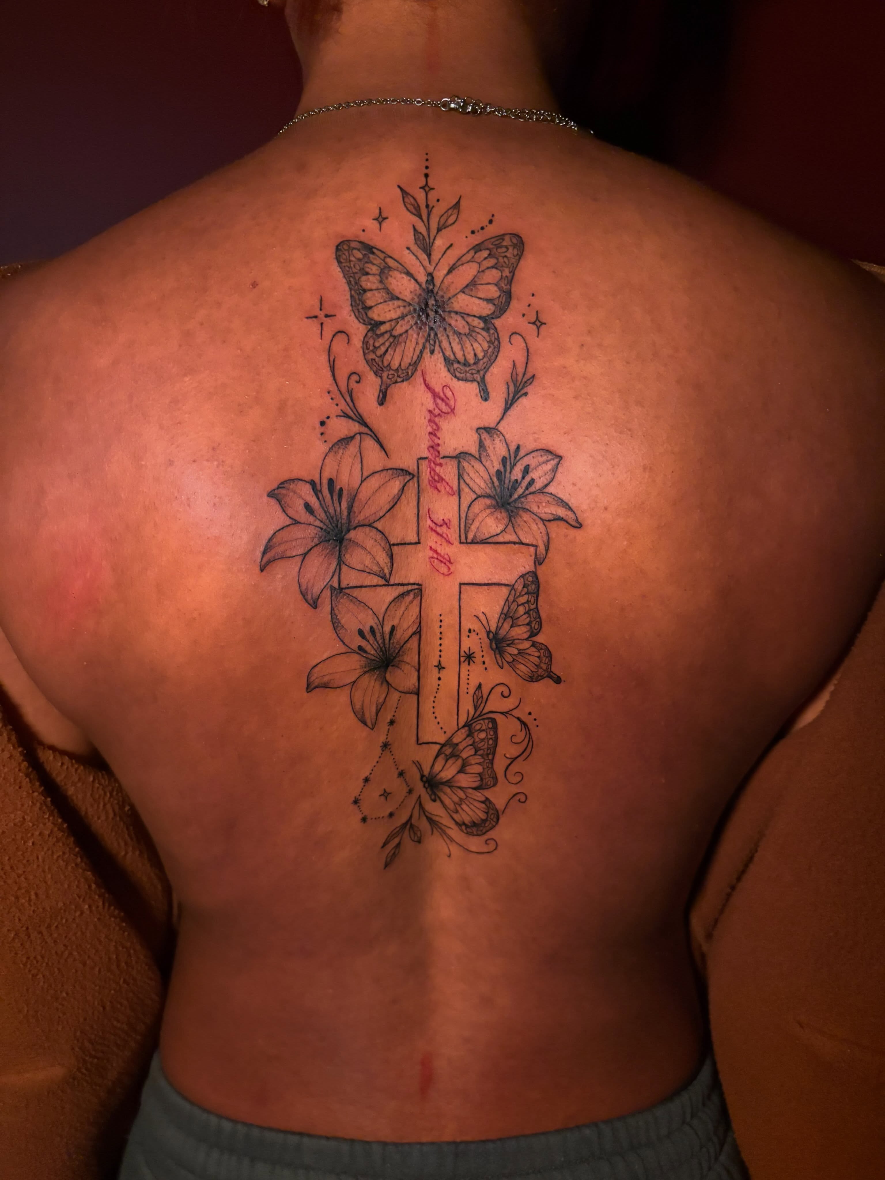 Cross with butterflies and lilies black and grey tattoo on the back by Kells