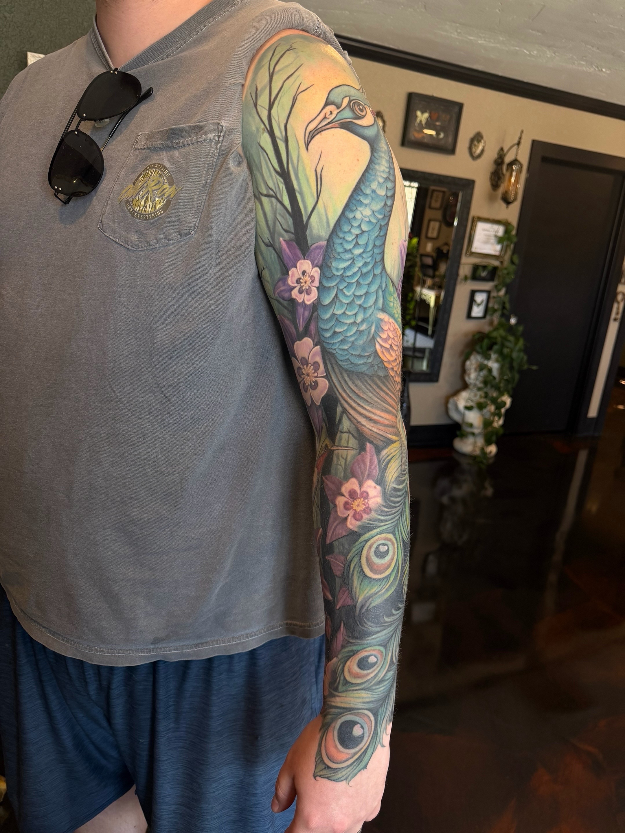 Peacock and floral new school tattoo on the upper arm by Shae Sullivan