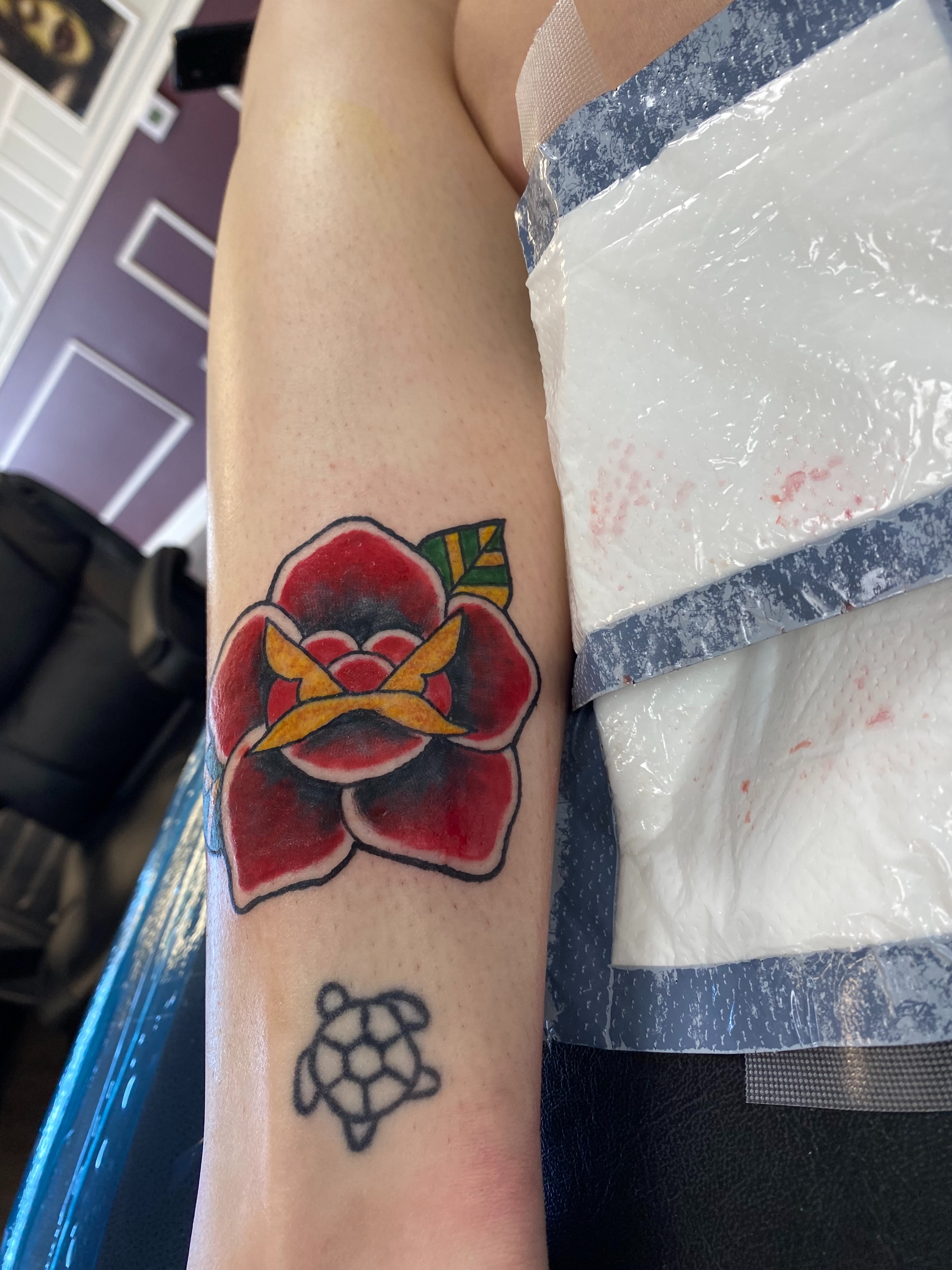 Red rose American traditional tattoo on the forearm by “tatsbysabby”