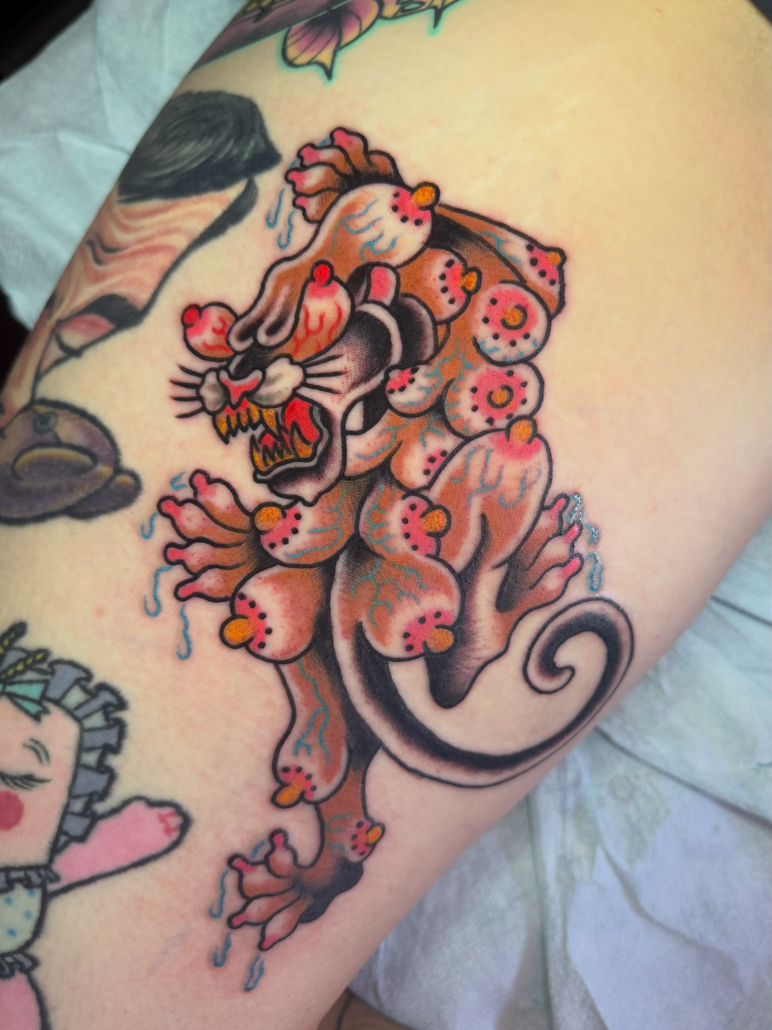 Lion and flowers American traditional tattoo on the thigh by Chris Bishop