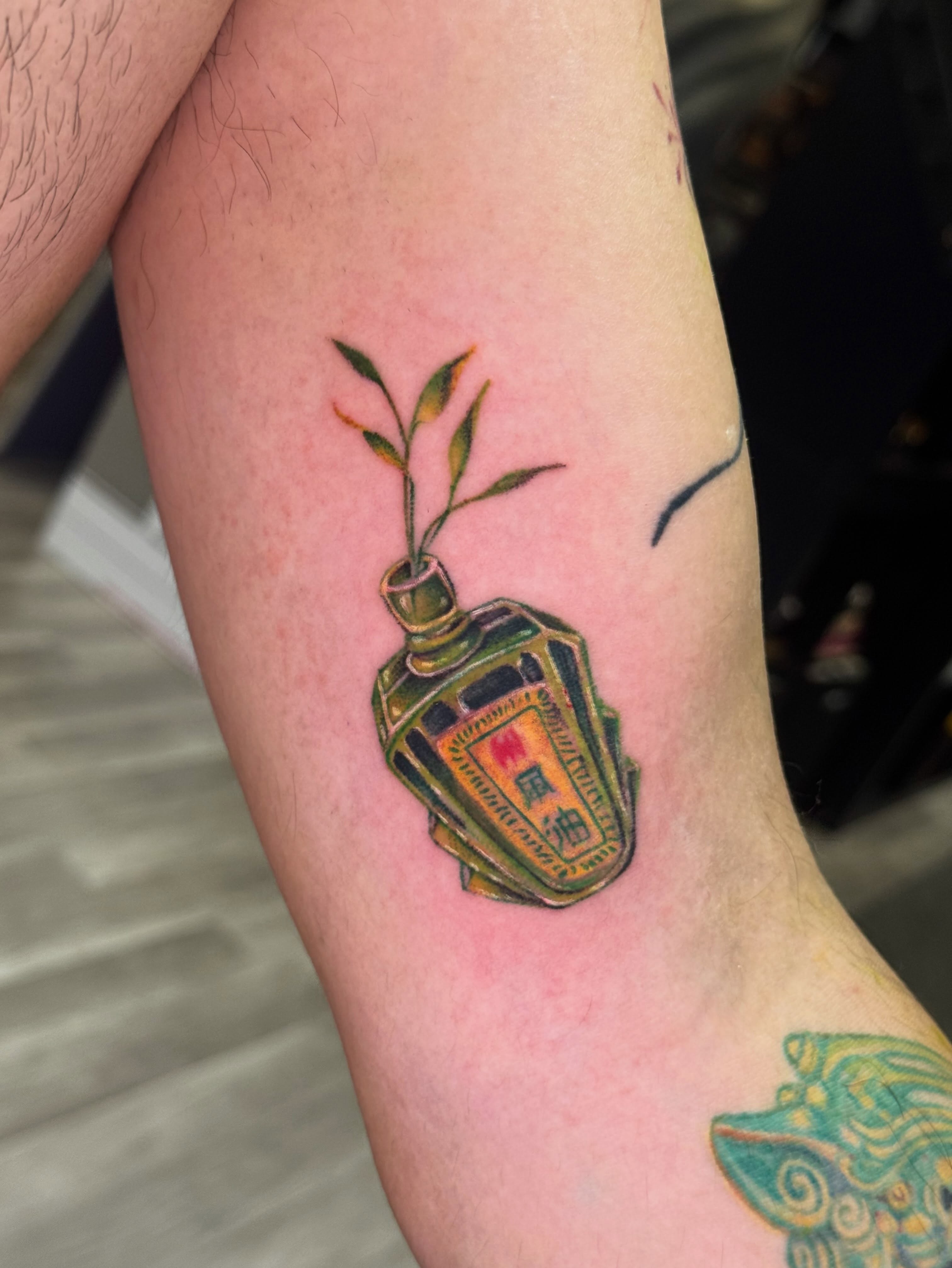 Bottle with plant realism tattoo on the forearm by Marie Amor🌙