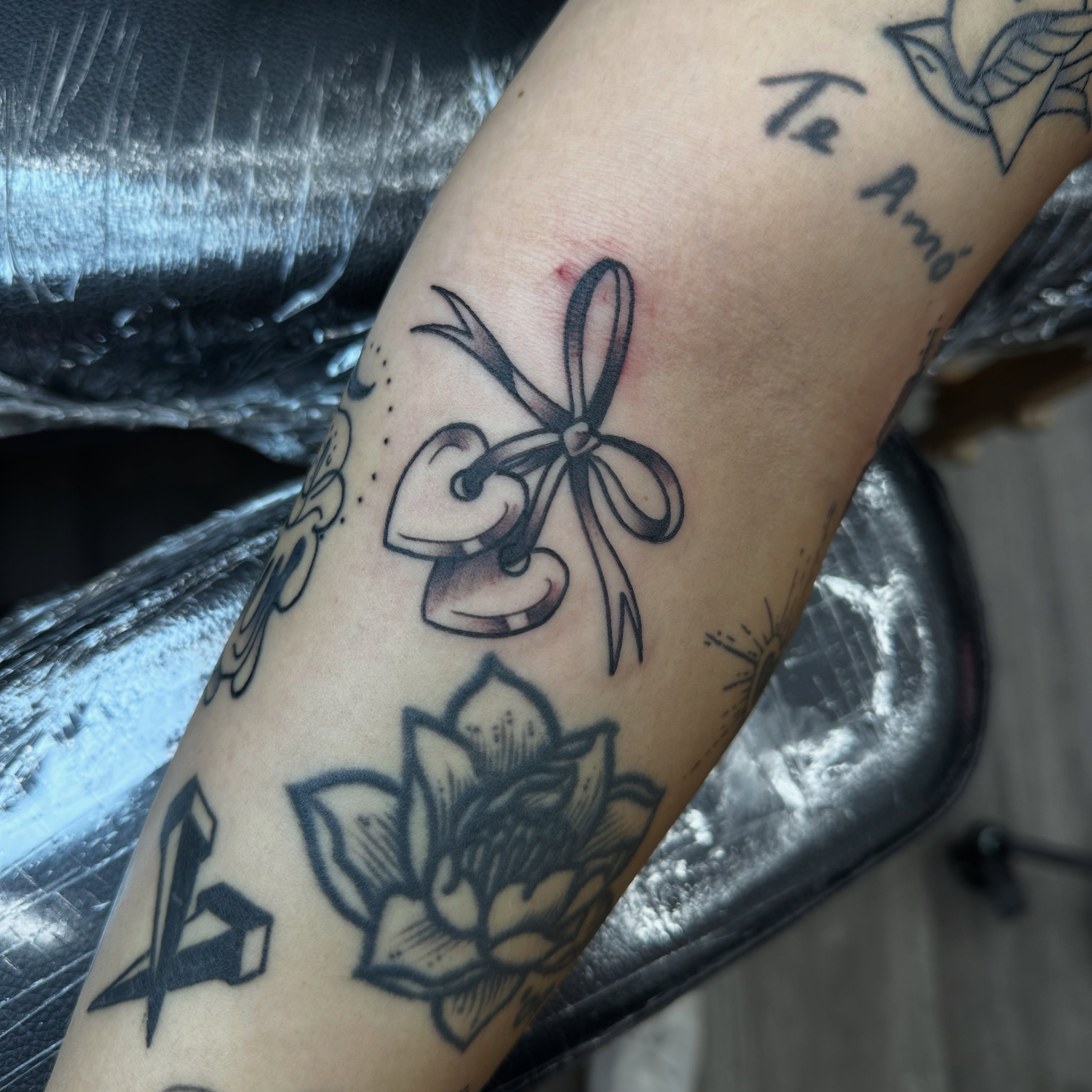Bow and heart black and grey tattoo on the forearm by Ash Nicole Painterly, San Diego, California