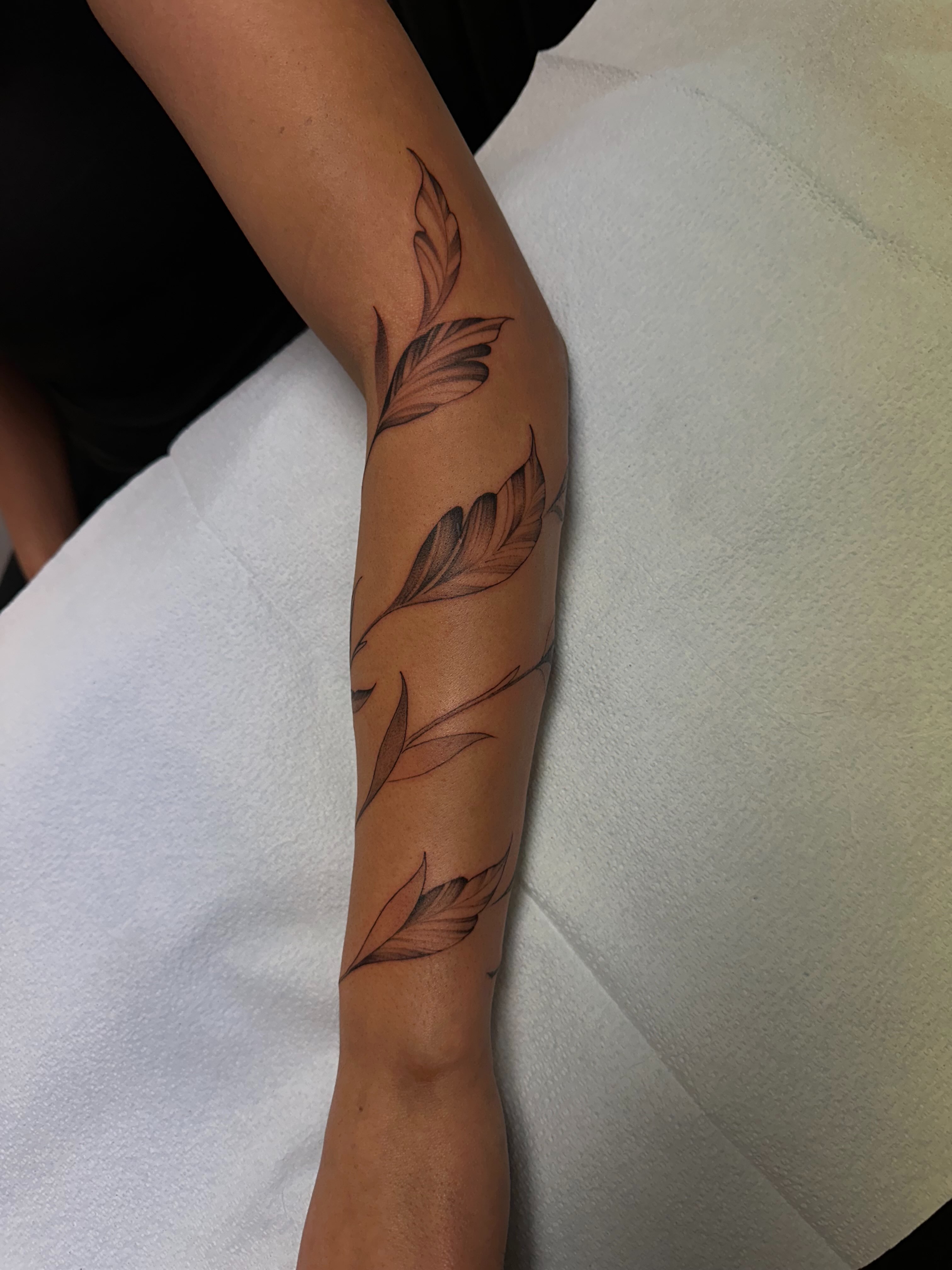 Feather black and grey tattoo on the forearm by Sebastian Livingston