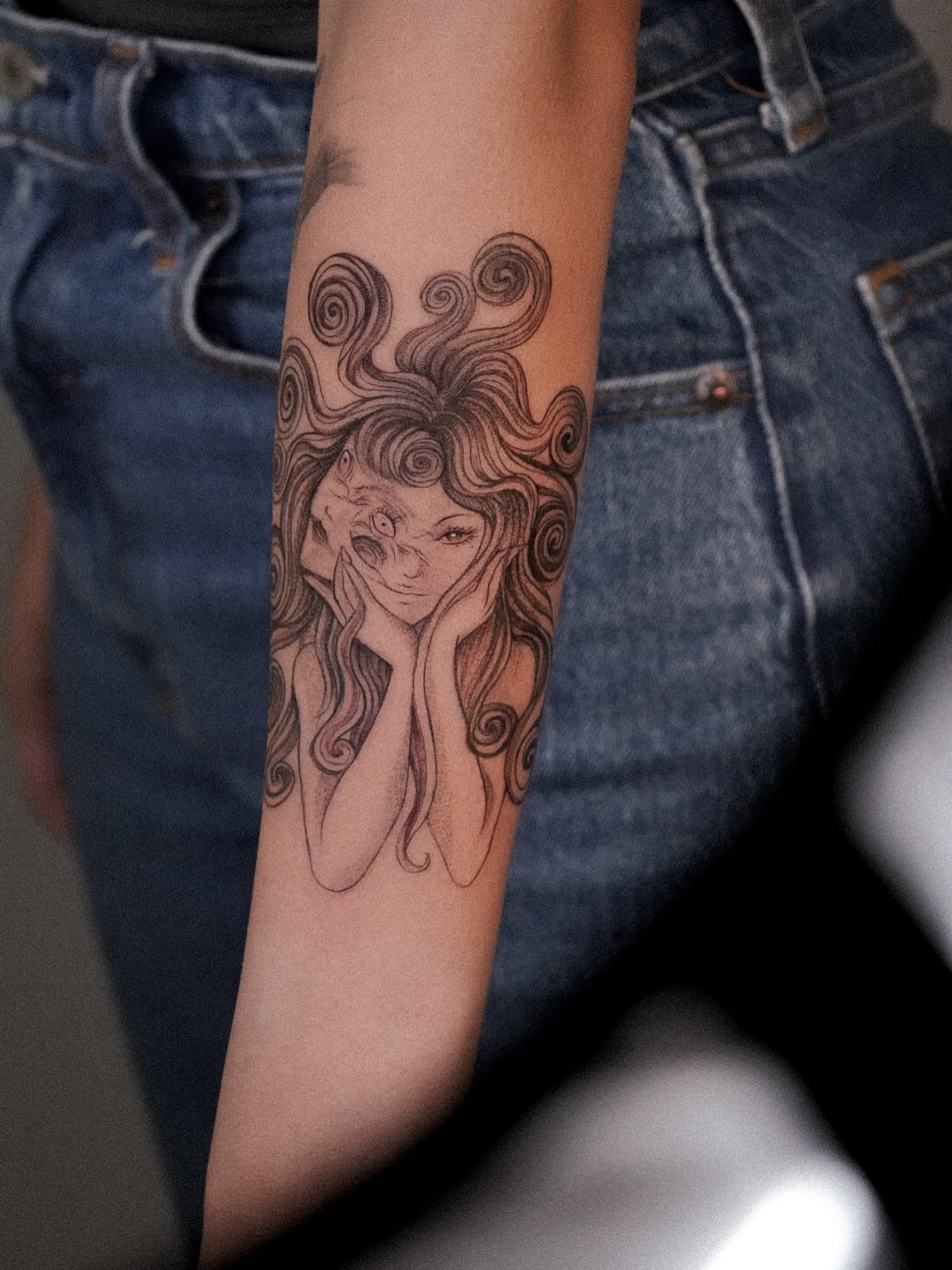 Woman with long hair black and grey tattoo on the forearm by Joy Christiana