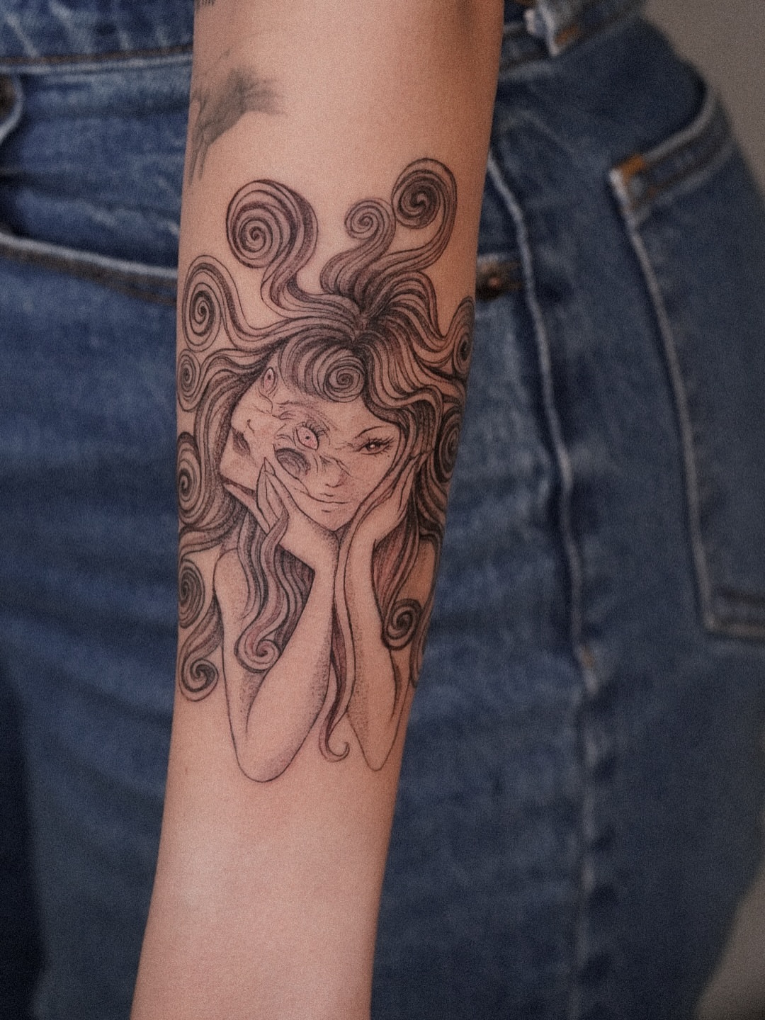 Woman with swirling hair black and grey tattoo on the forearm by Joy Christiana