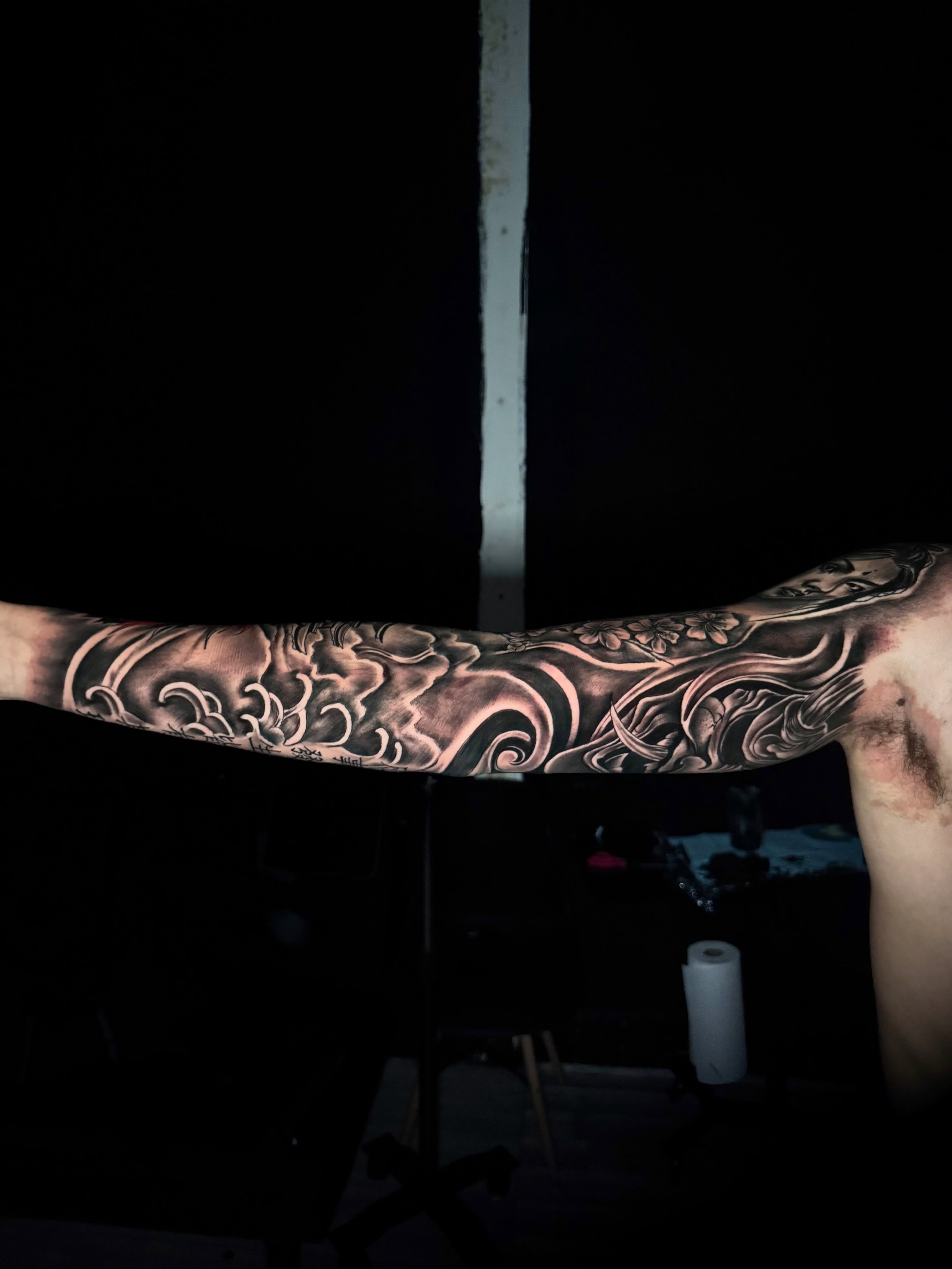 Floral and wave pattern black and grey tattoo on the upper arm by Zeus