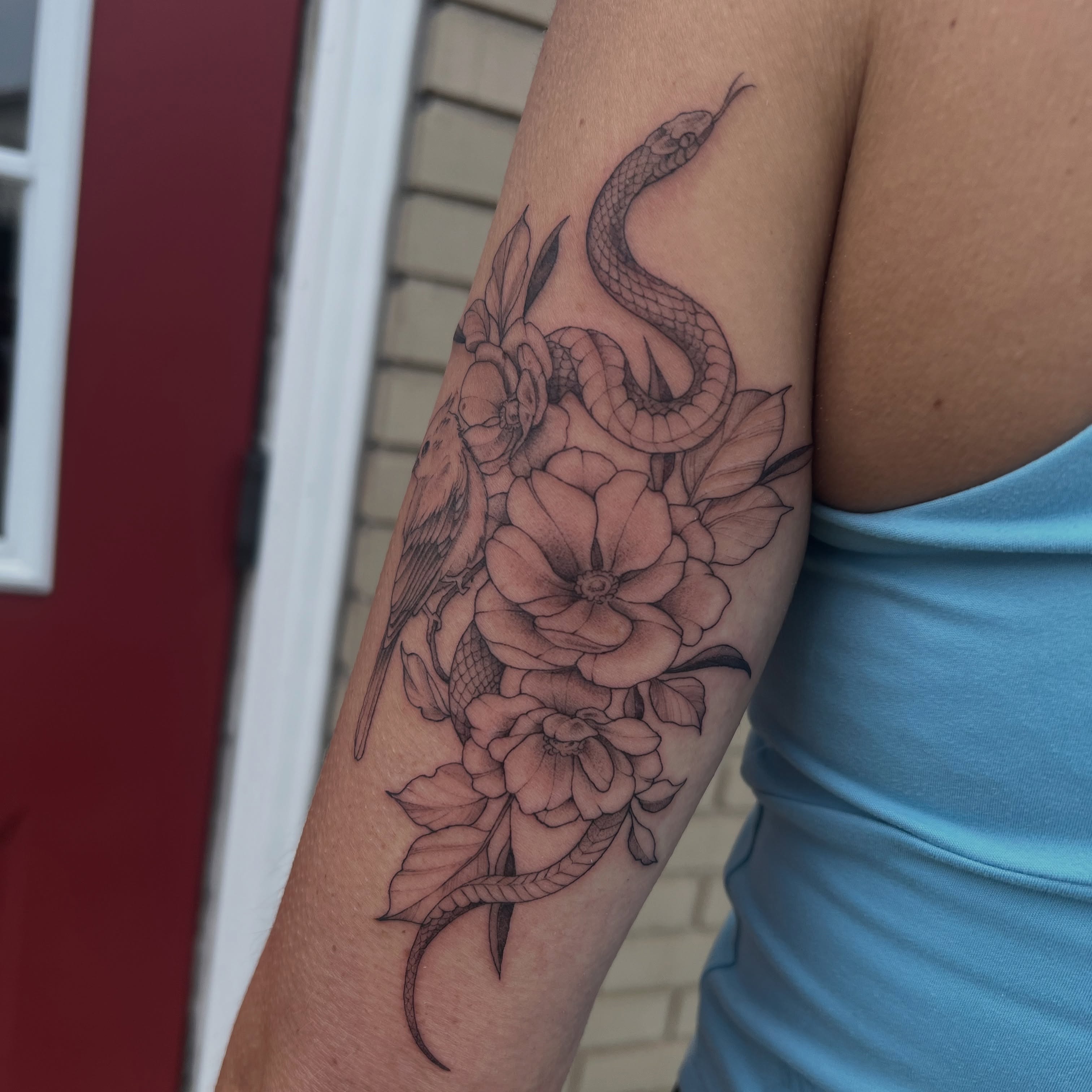 Snake and flowers realism tattoo on the forearm by Dom