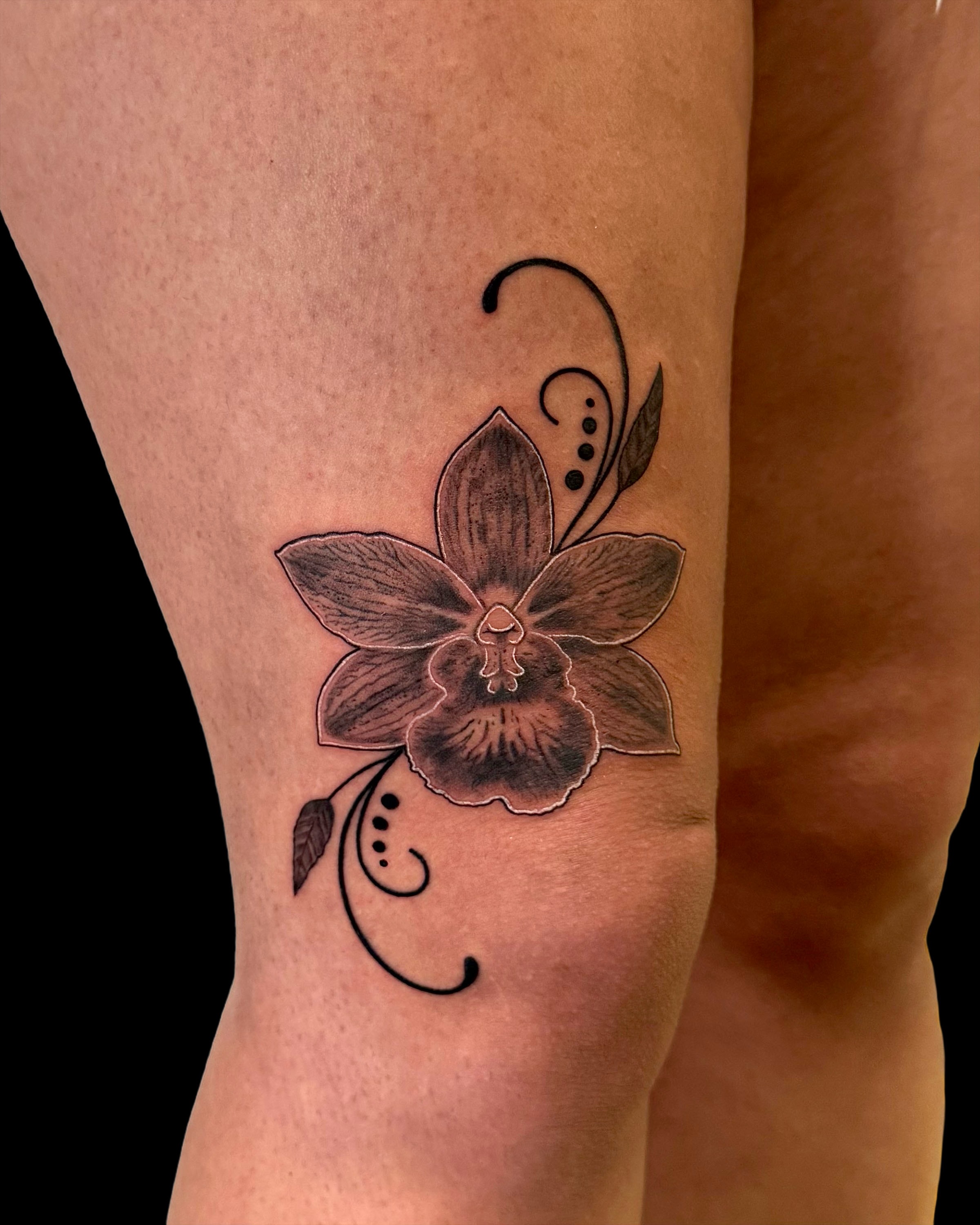 Orchid black and grey tattoo on the thigh by Too Zen