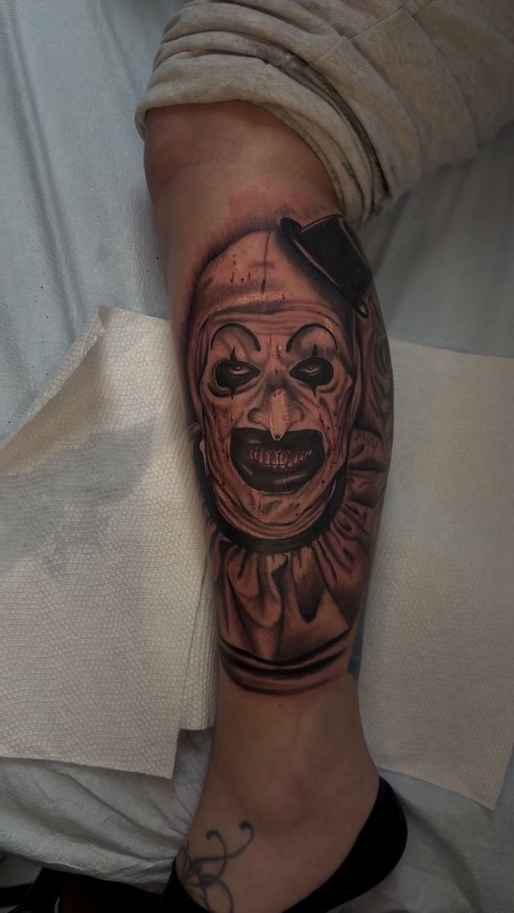 Creepy clown face dark realism tattoo by Alyssa Turner