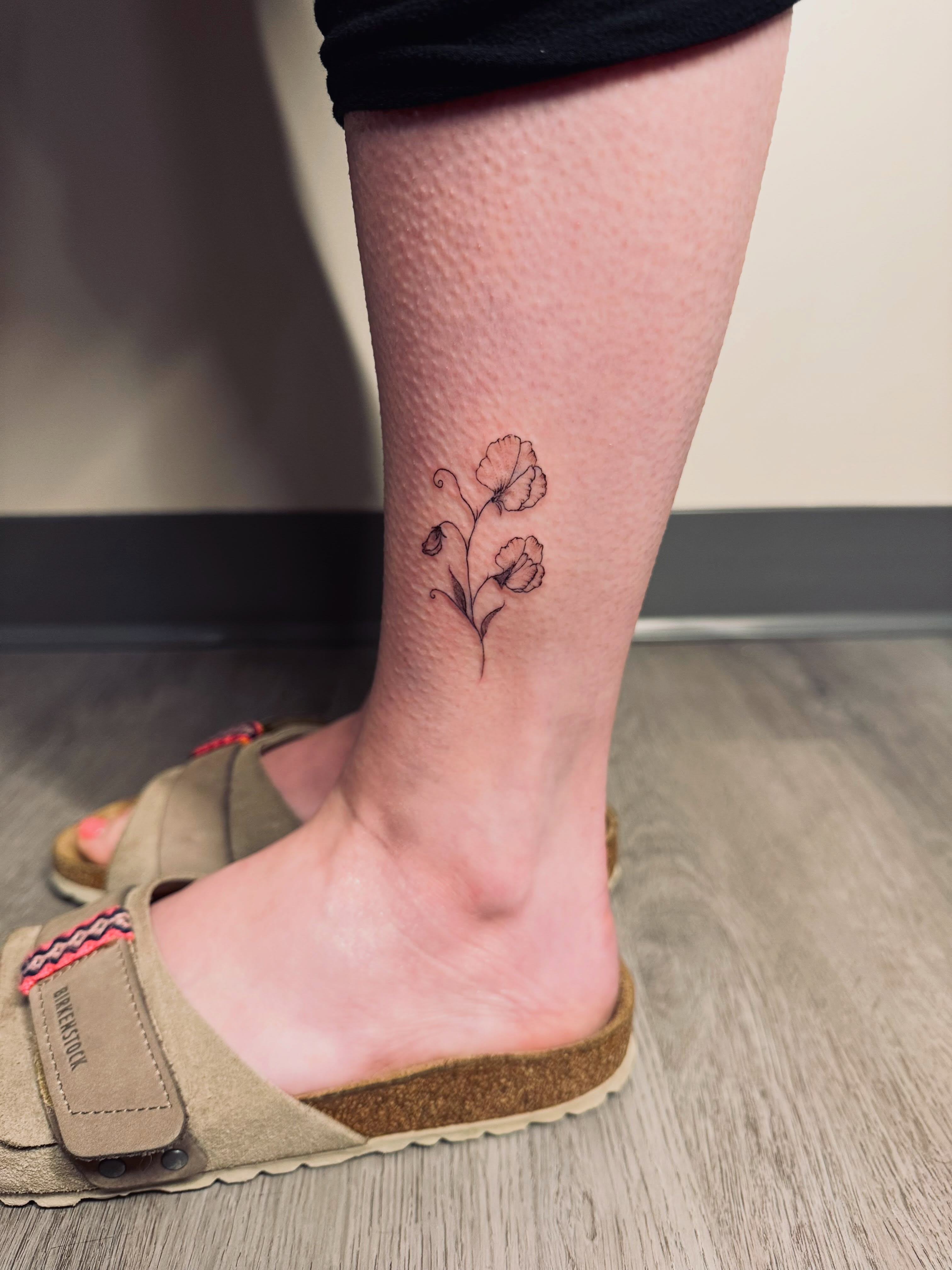 Poppy flowers fine line tattoo on the calf by Ashley Pilgreen