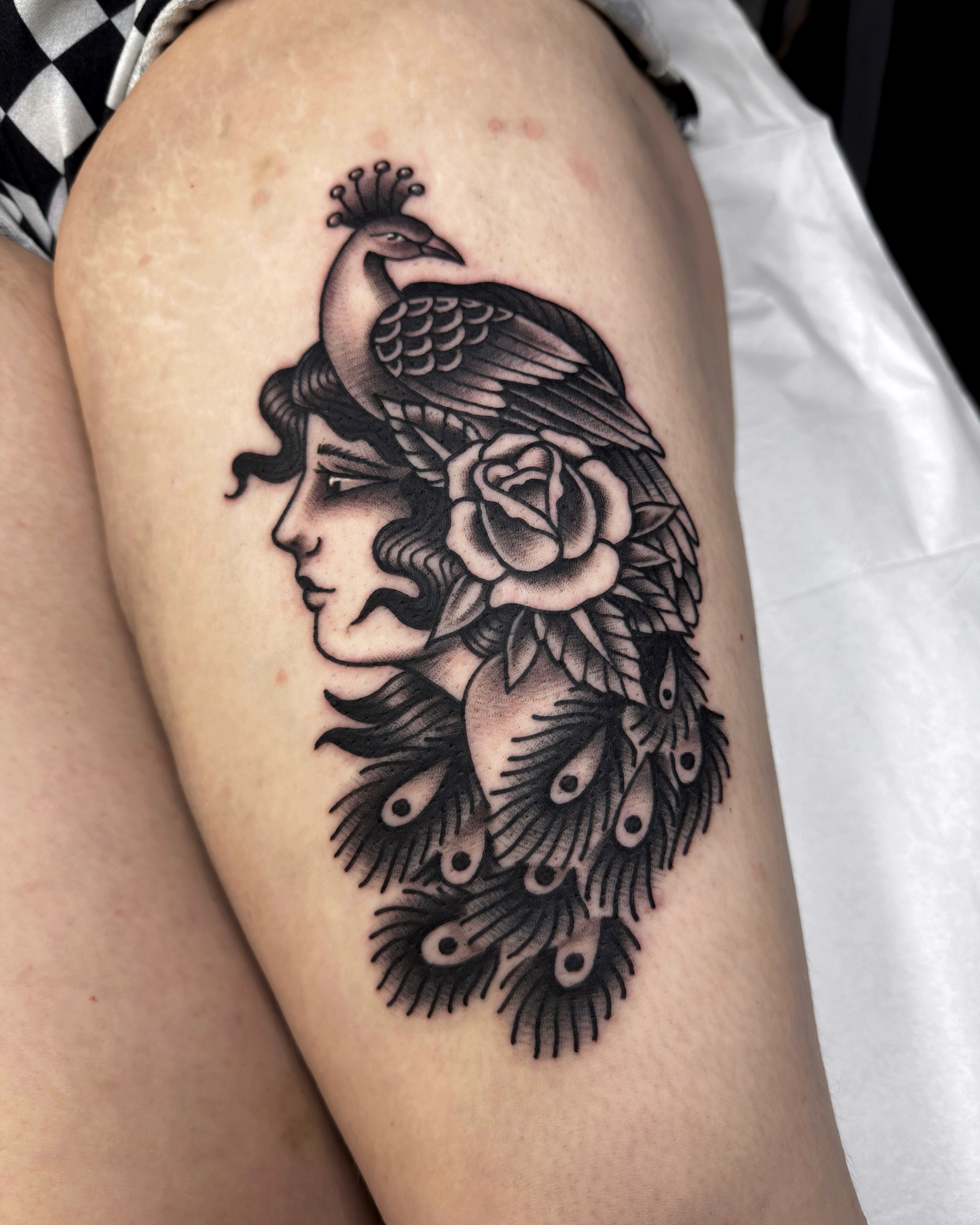 Peacock and woman realism tattoo on the thigh by Trav, Bayville, New Jersey