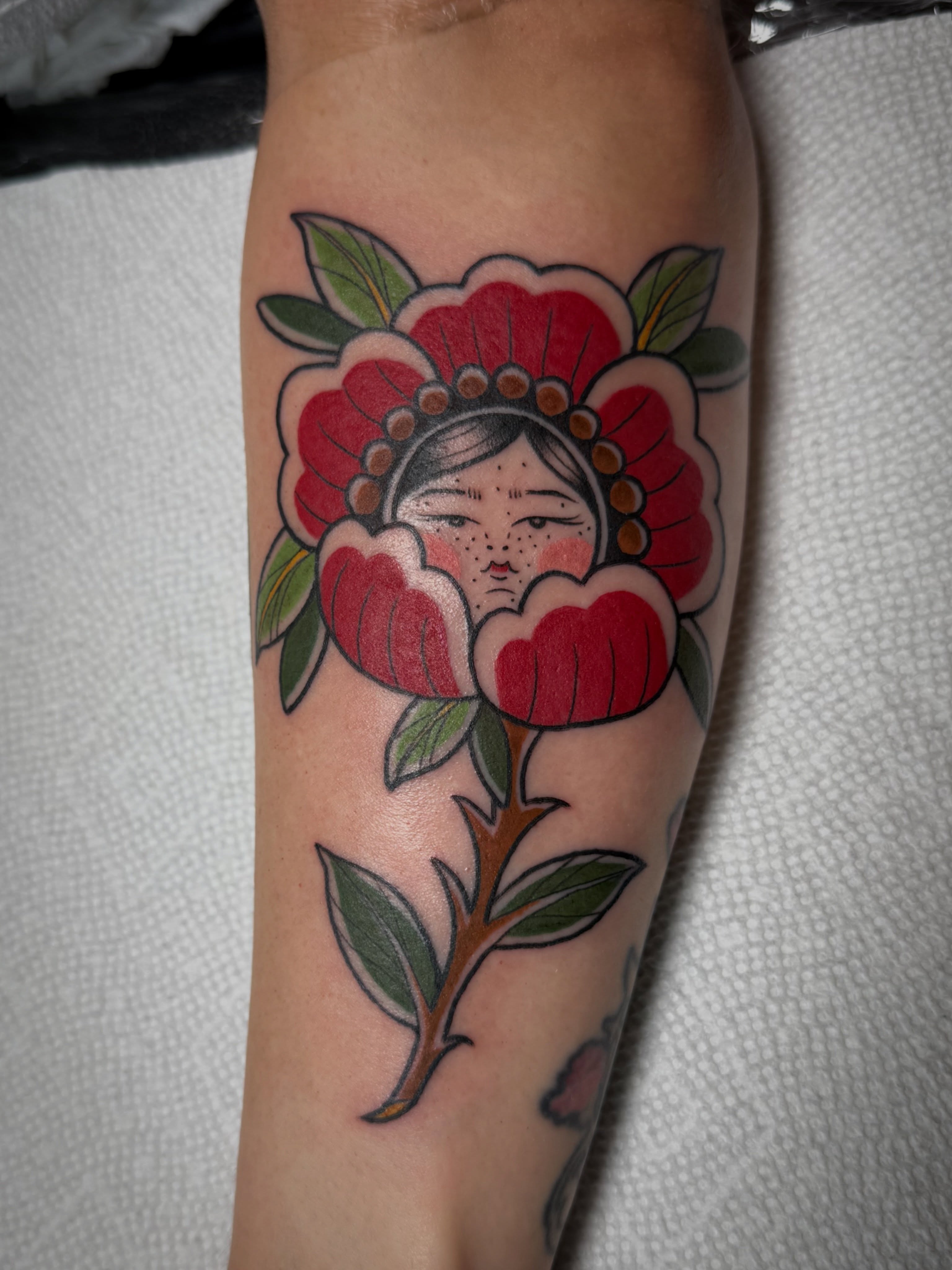 Flower with face American traditional tattoo on the forearm by Leah - Tattoo Artist