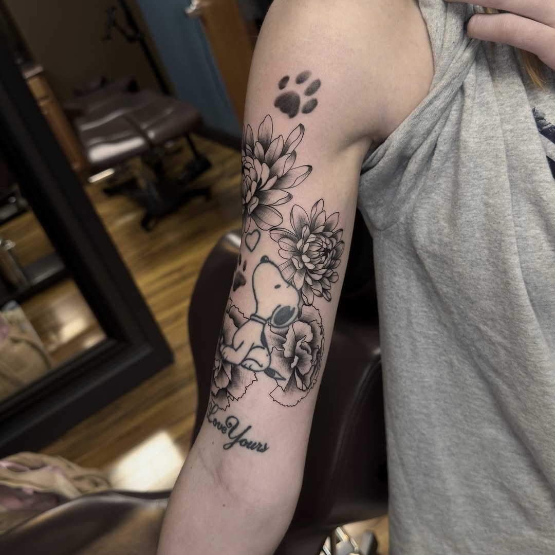 Snoopy with flowers black and grey tattoo on the forearm by Leo Fernandes, Danvers, Massachusetts