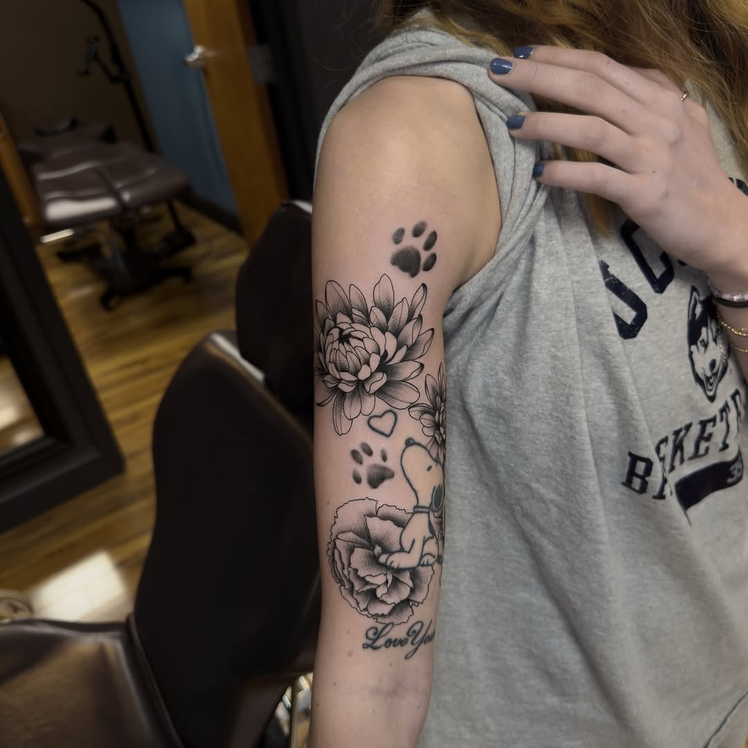 Flowers and Snoopy black and grey tattoo on the upper arm by Leo Fernandes, Danvers, Massachusetts