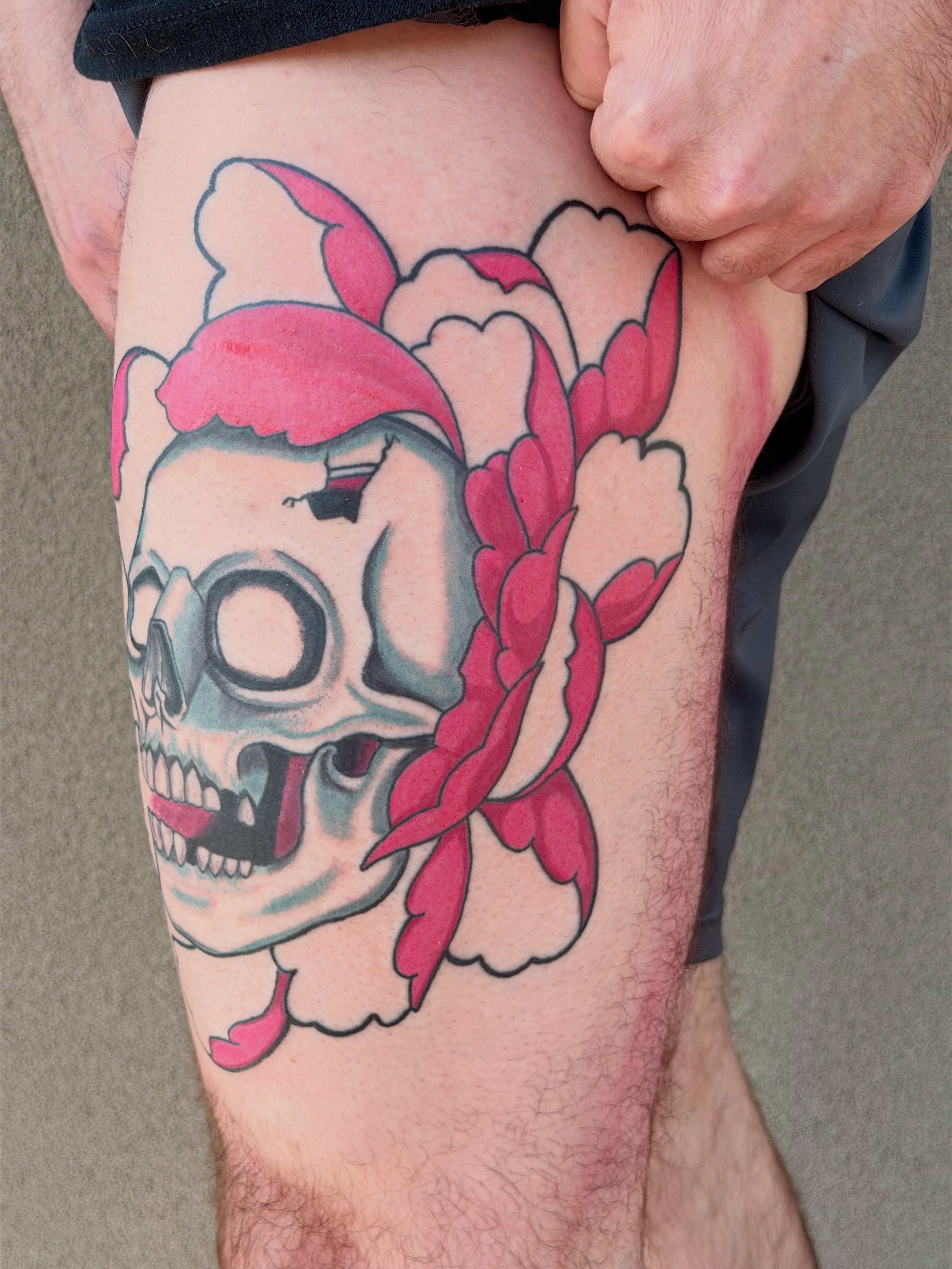 Skull with pink flowers American traditional tattoo on the thigh by Ellari