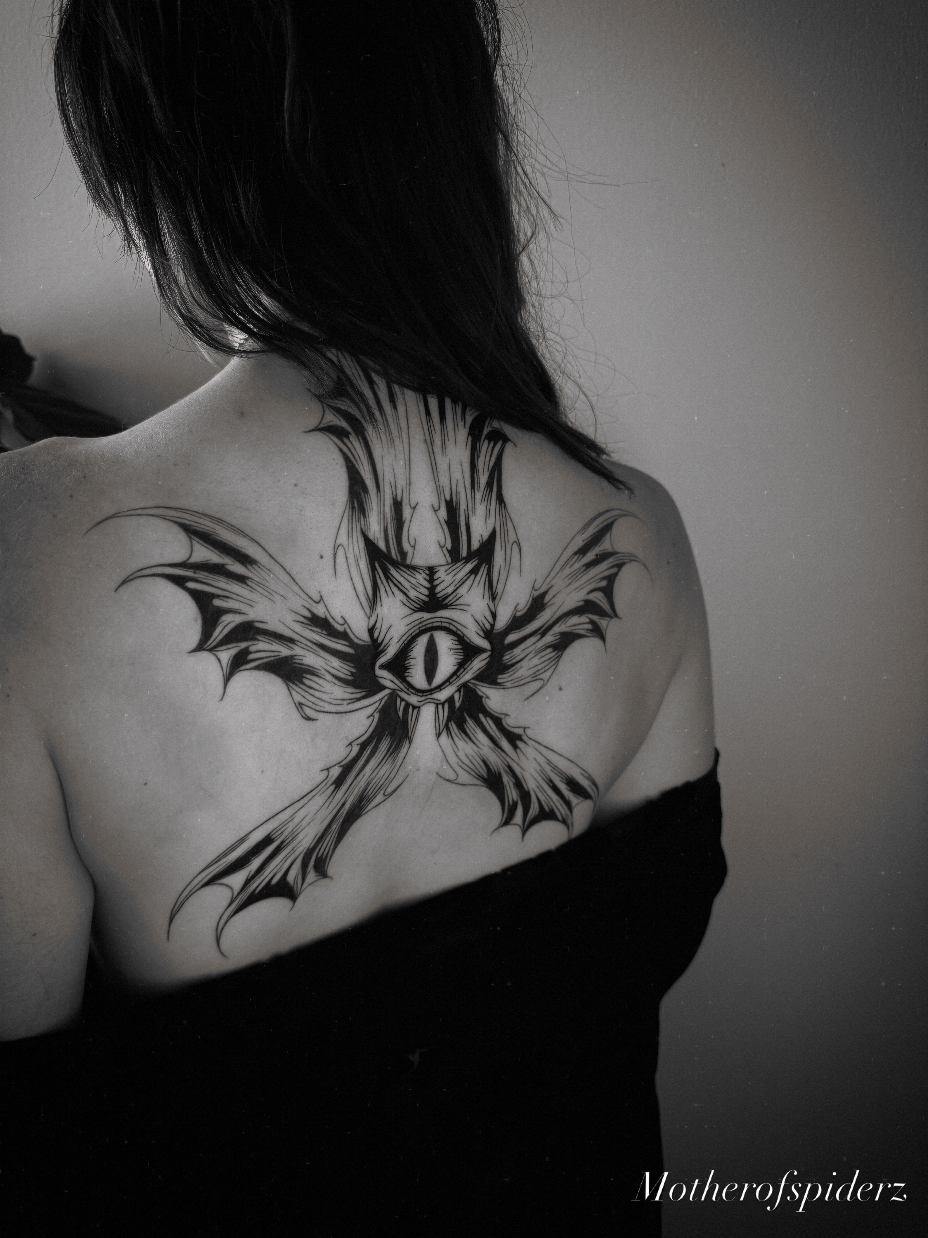 Eye with bat wings black and grey tattoo on the back by Alyssa Garza