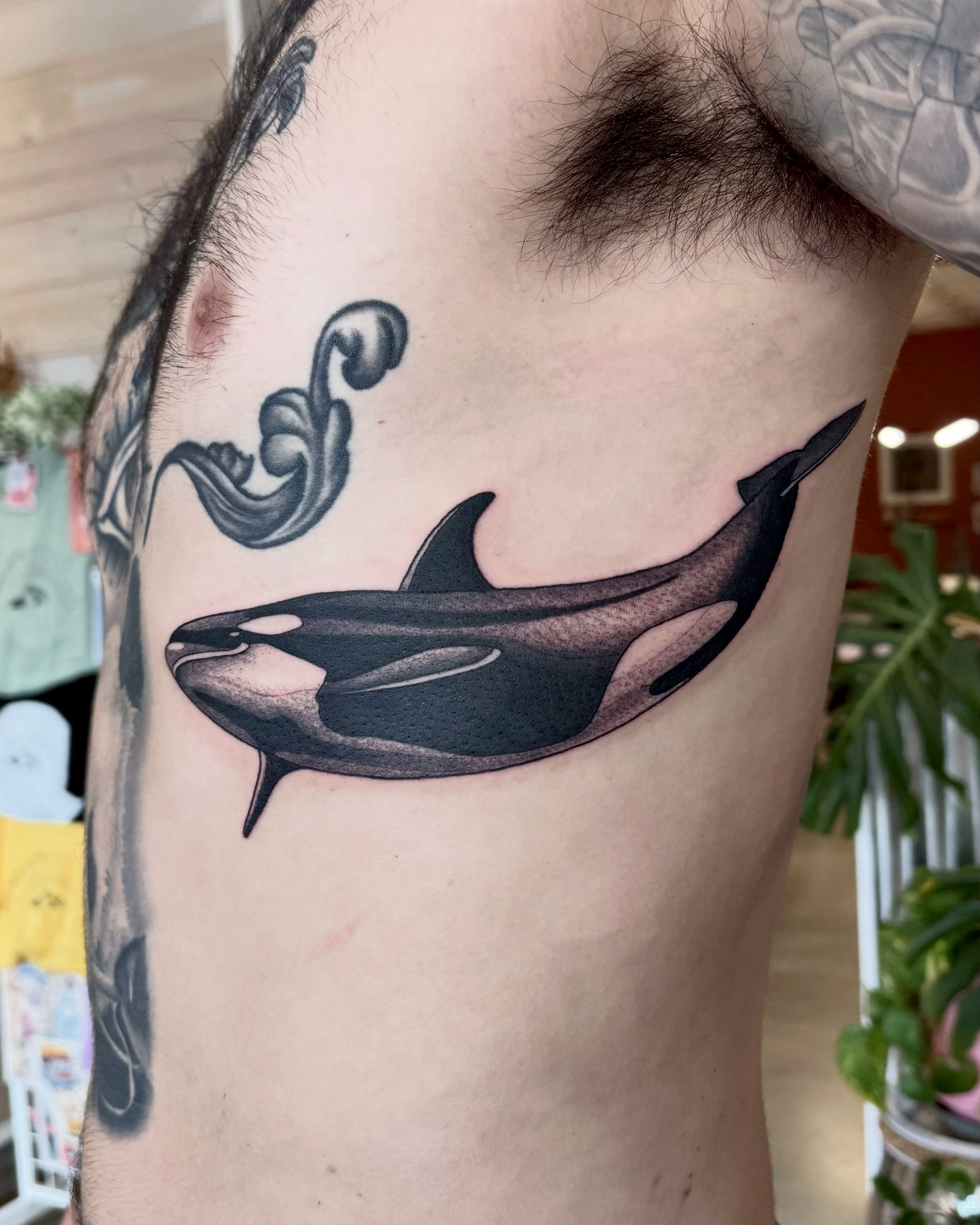 Orca whale black and grey tattoo on the upper arm by Eden Allen