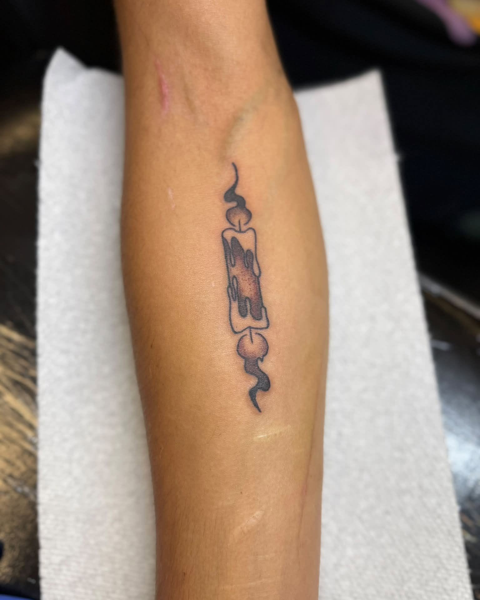 Melting candle black and grey tattoo on the forearm by Israel Jacob Woehler