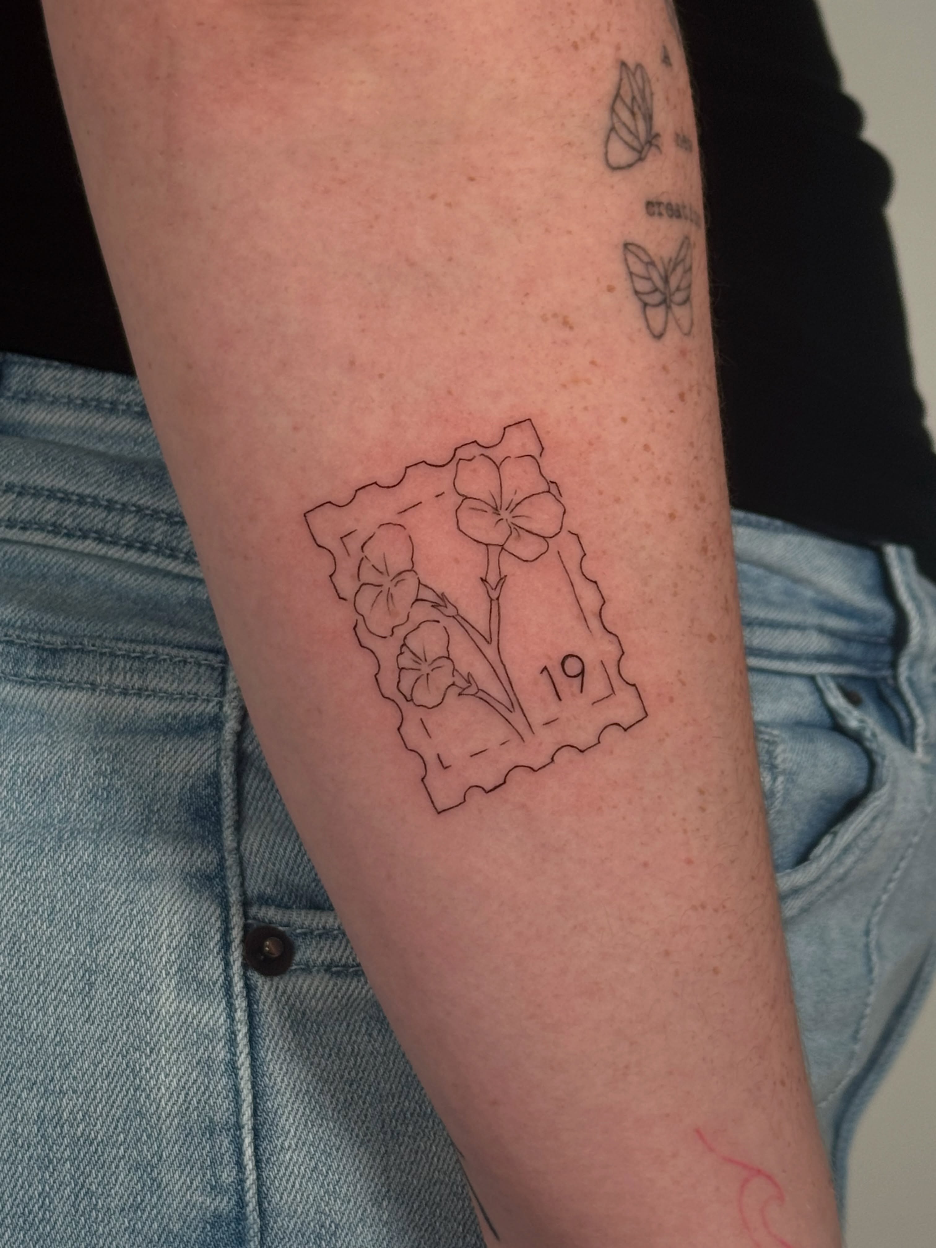 Flower postage stamp fine line tattoo on the forearm by Jules Ink ⋆ Fineline Tattoo