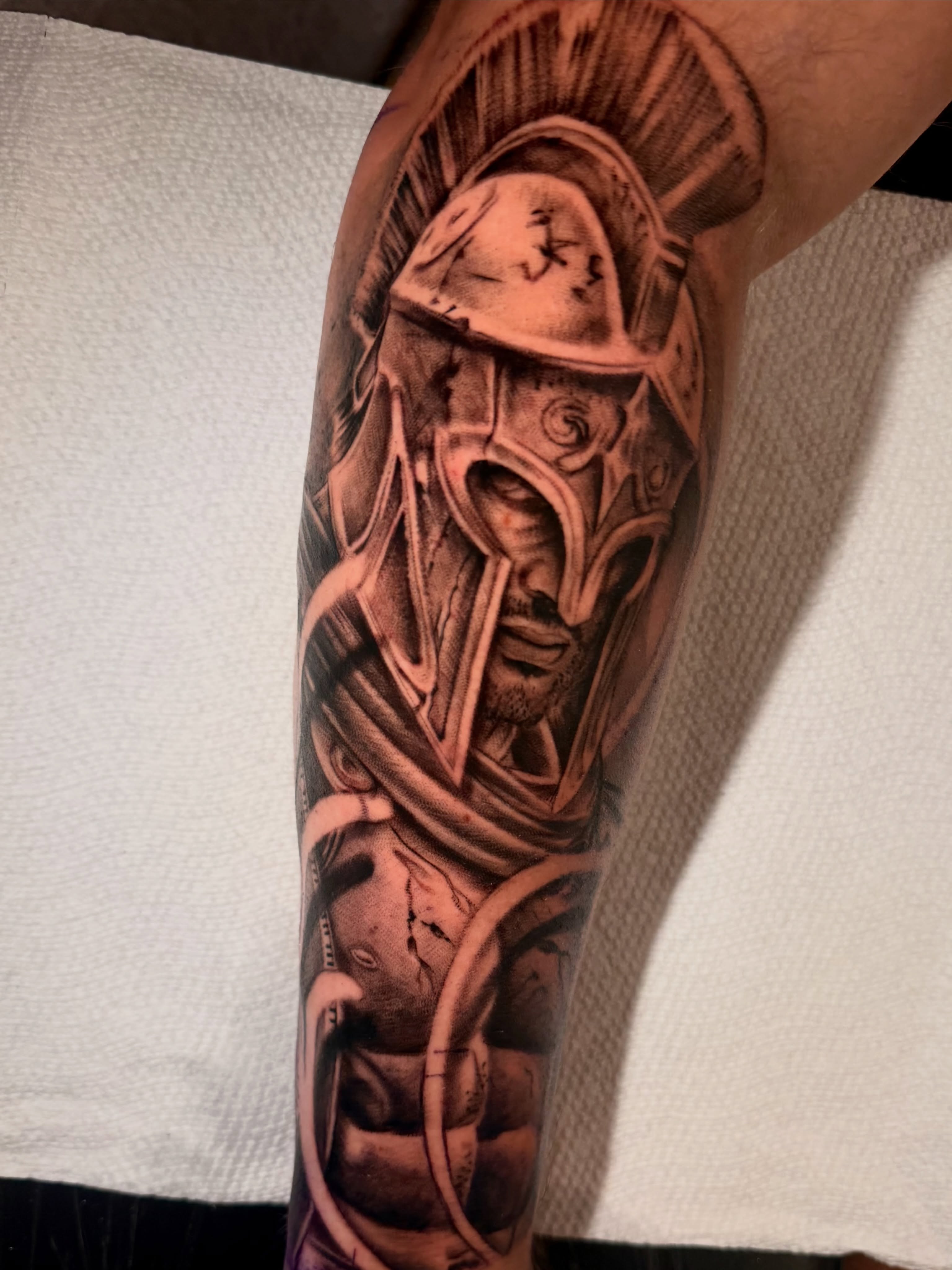 Helmeted warrior realism tattoo on the forearm by Jacob Sass