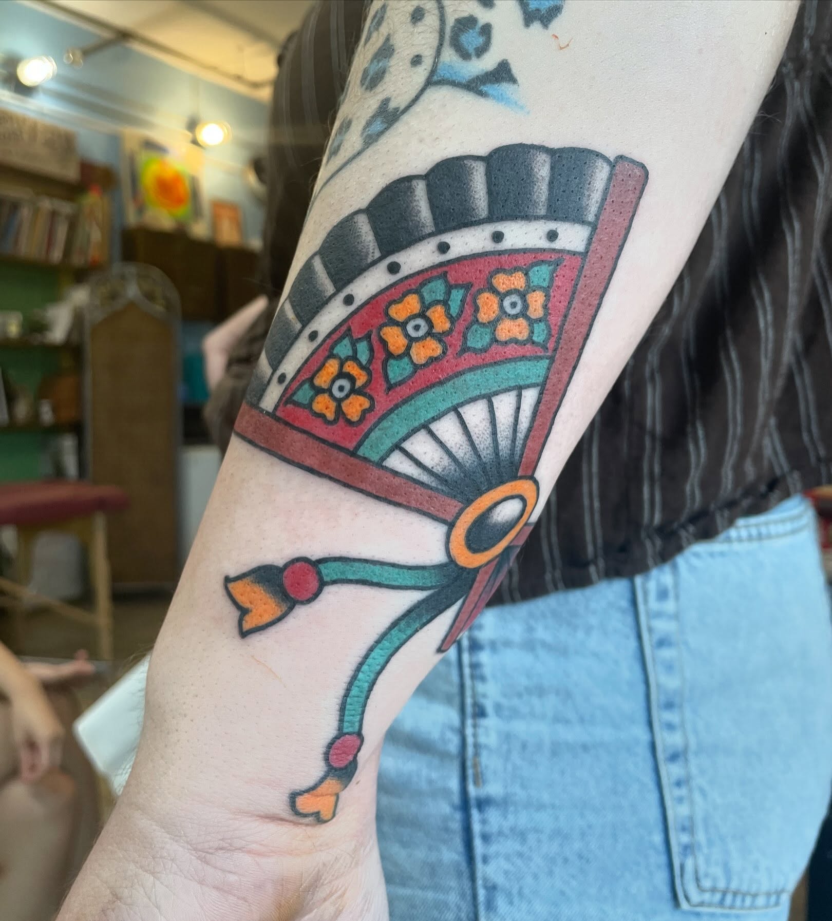 Fan American traditional tattoo on the forearm by Lainy Lou