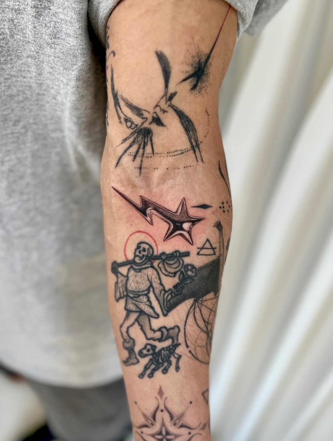 Skeletons carrying a star black and grey tattoo on the forearm by Soy 🫛