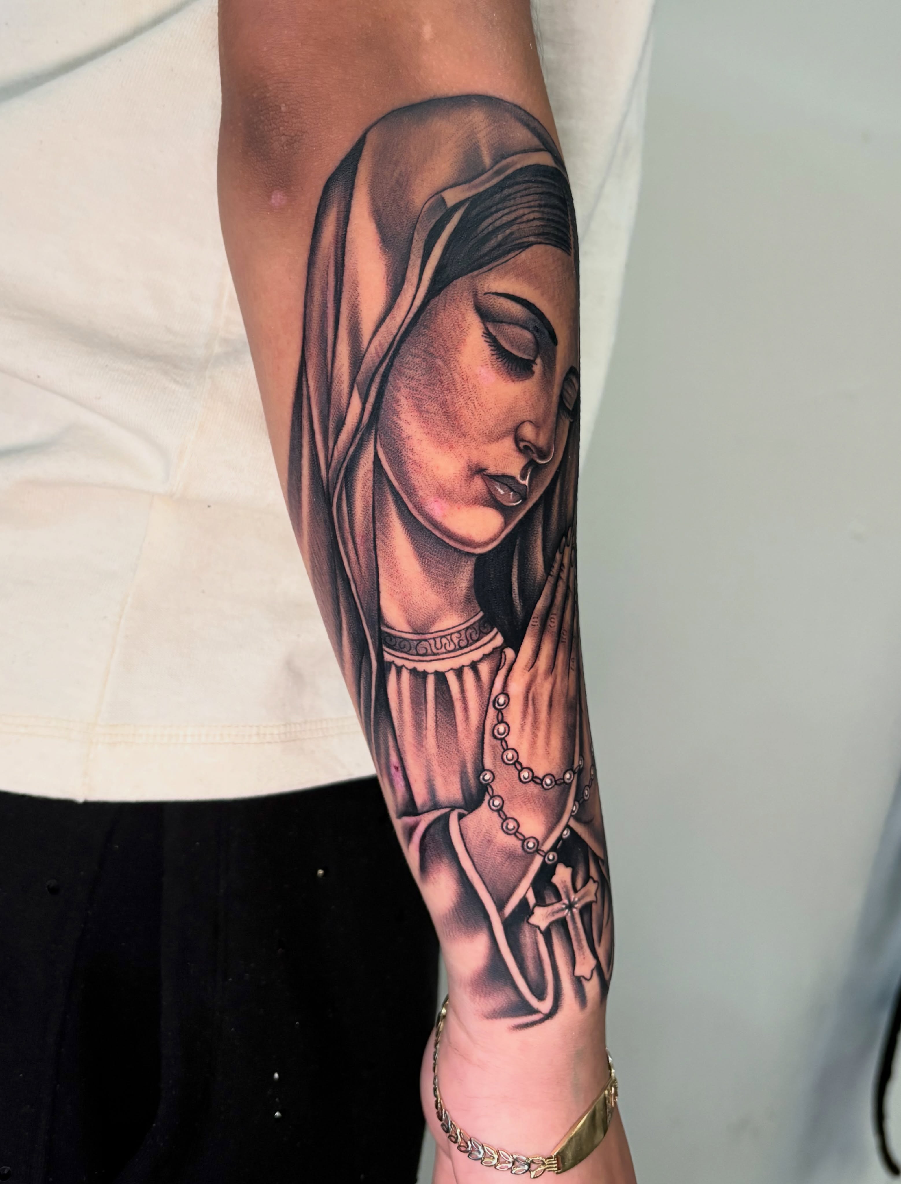 Religious figure praying realism tattoo on the forearm by Osiel Rodriguez