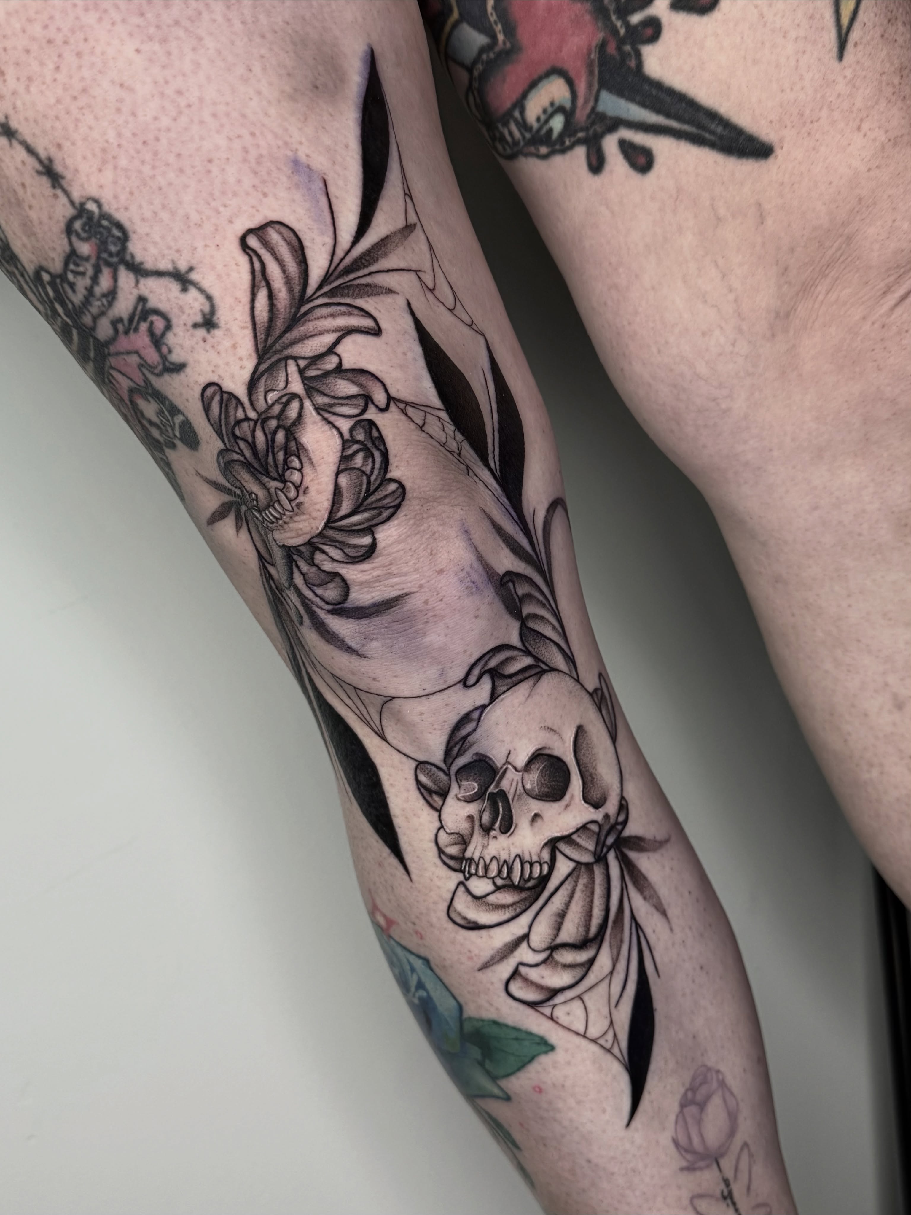 Skull and floral black and grey tattoo on the forearm by Kyleigh Shurak