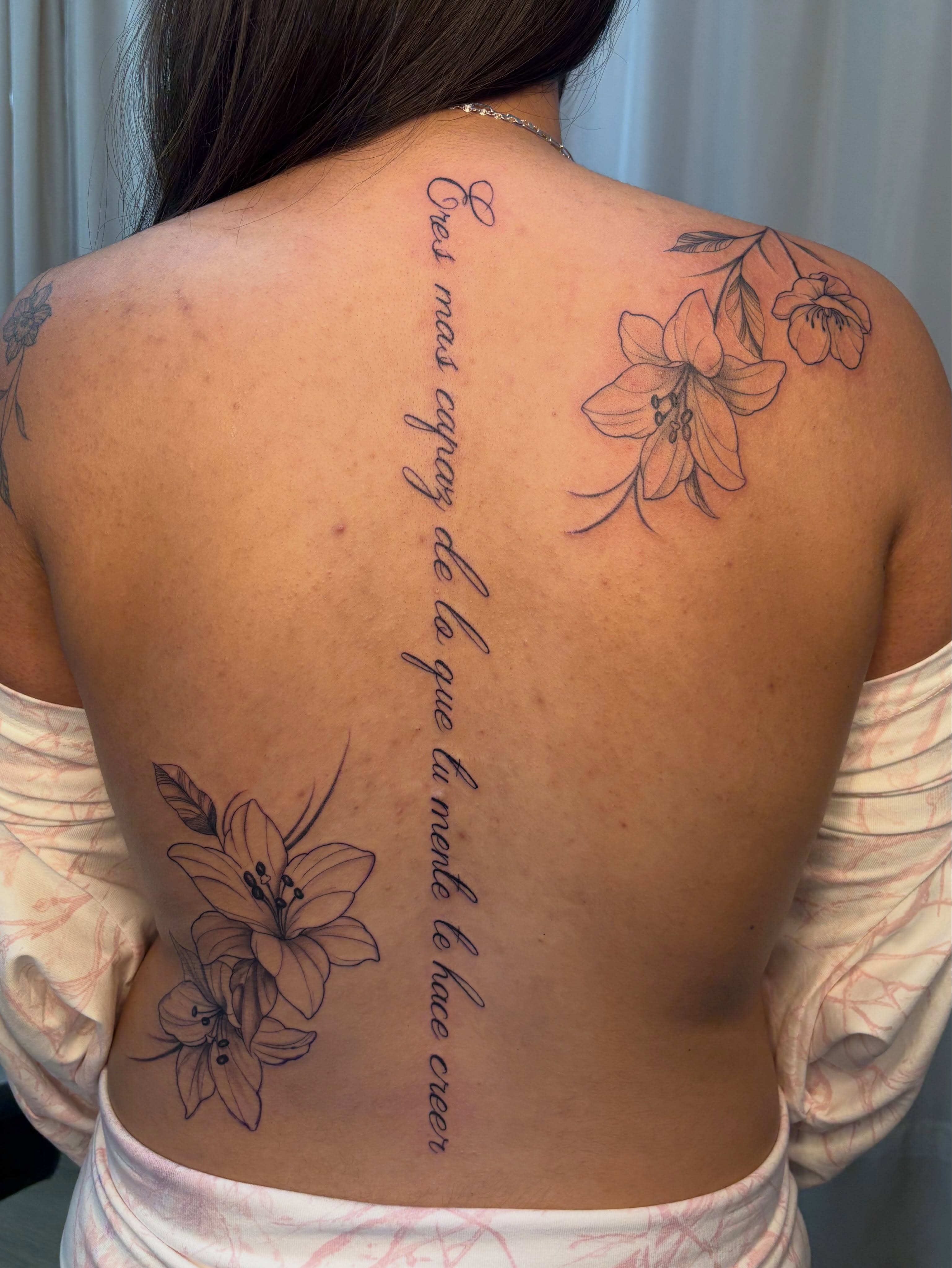 Lily flowers and script black and grey tattoo on the back by Jackie π€