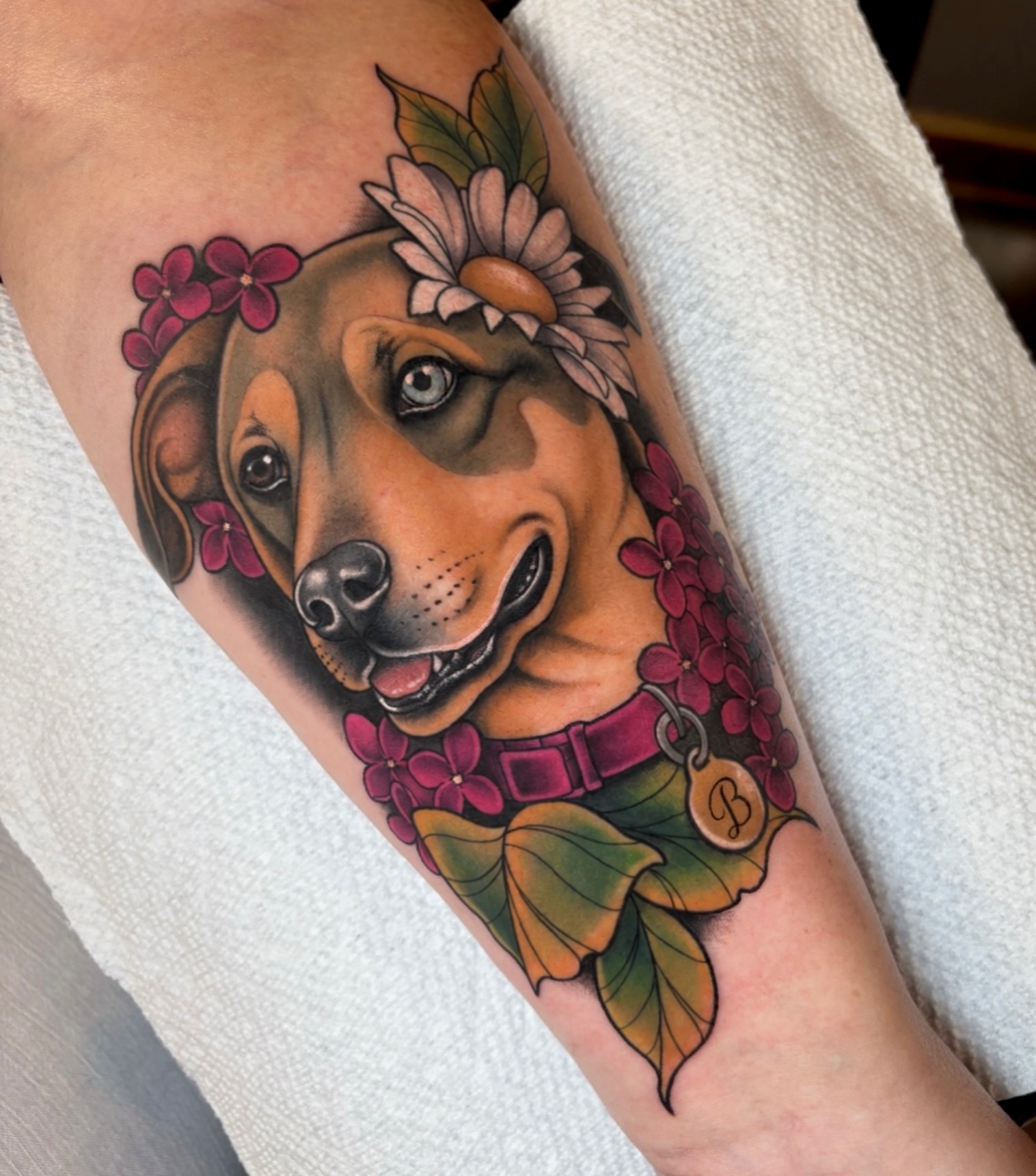 Dog with flowers realism tattoo on the forearm by ππππππ