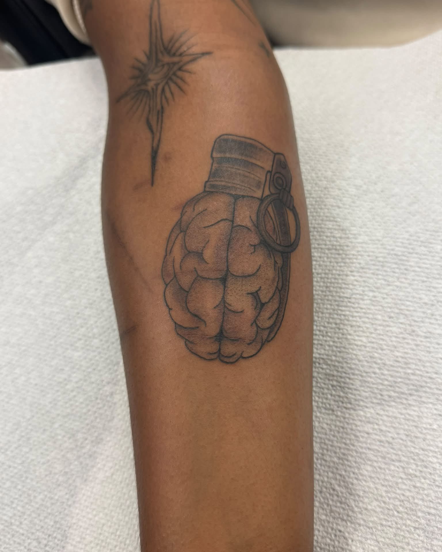 Hand grenade black and grey tattoo on the forearm by Israel Jacob Woehler