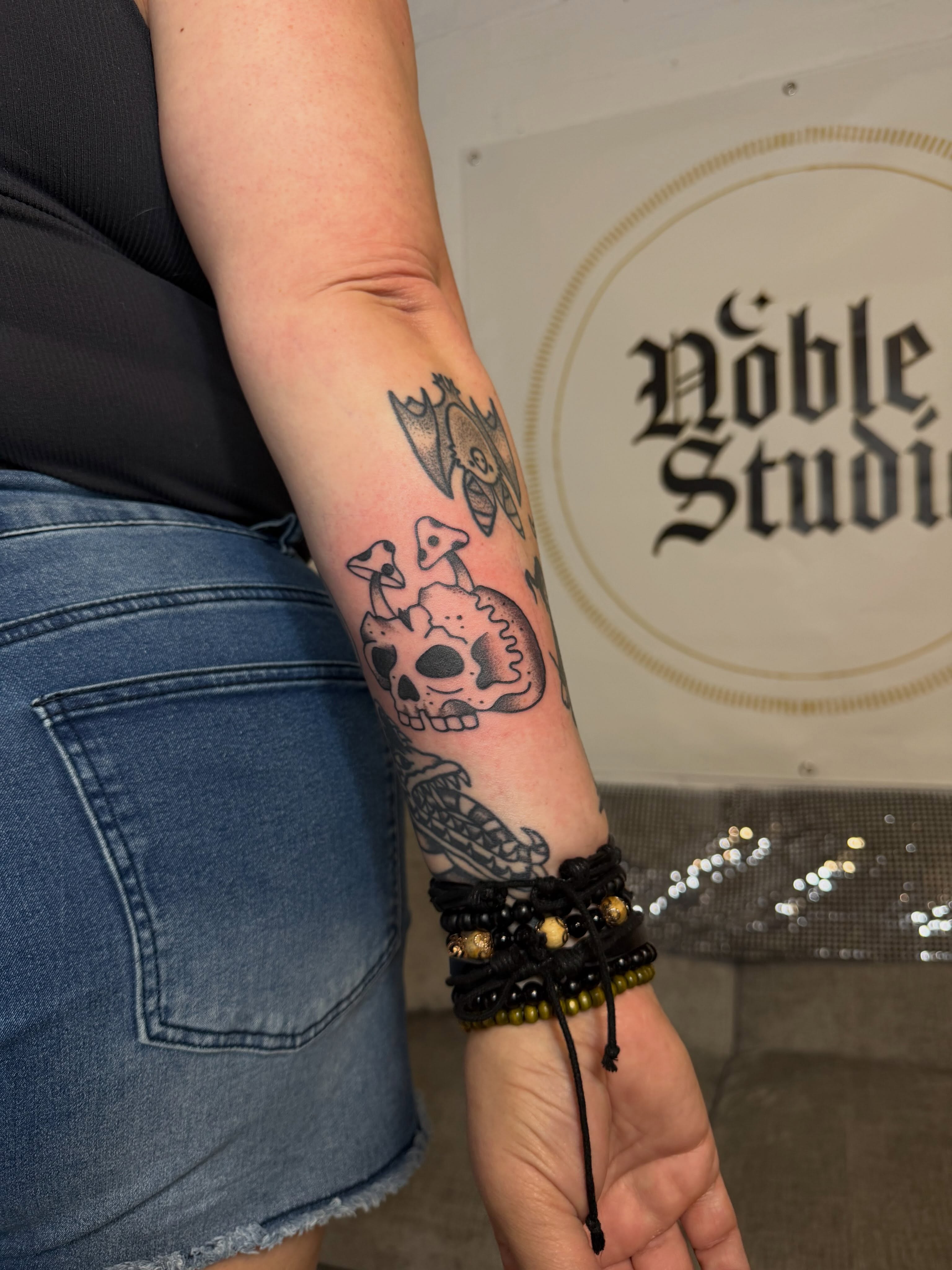 Skull and mushrooms black and grey tattoo on the forearm by Dennis Patterson