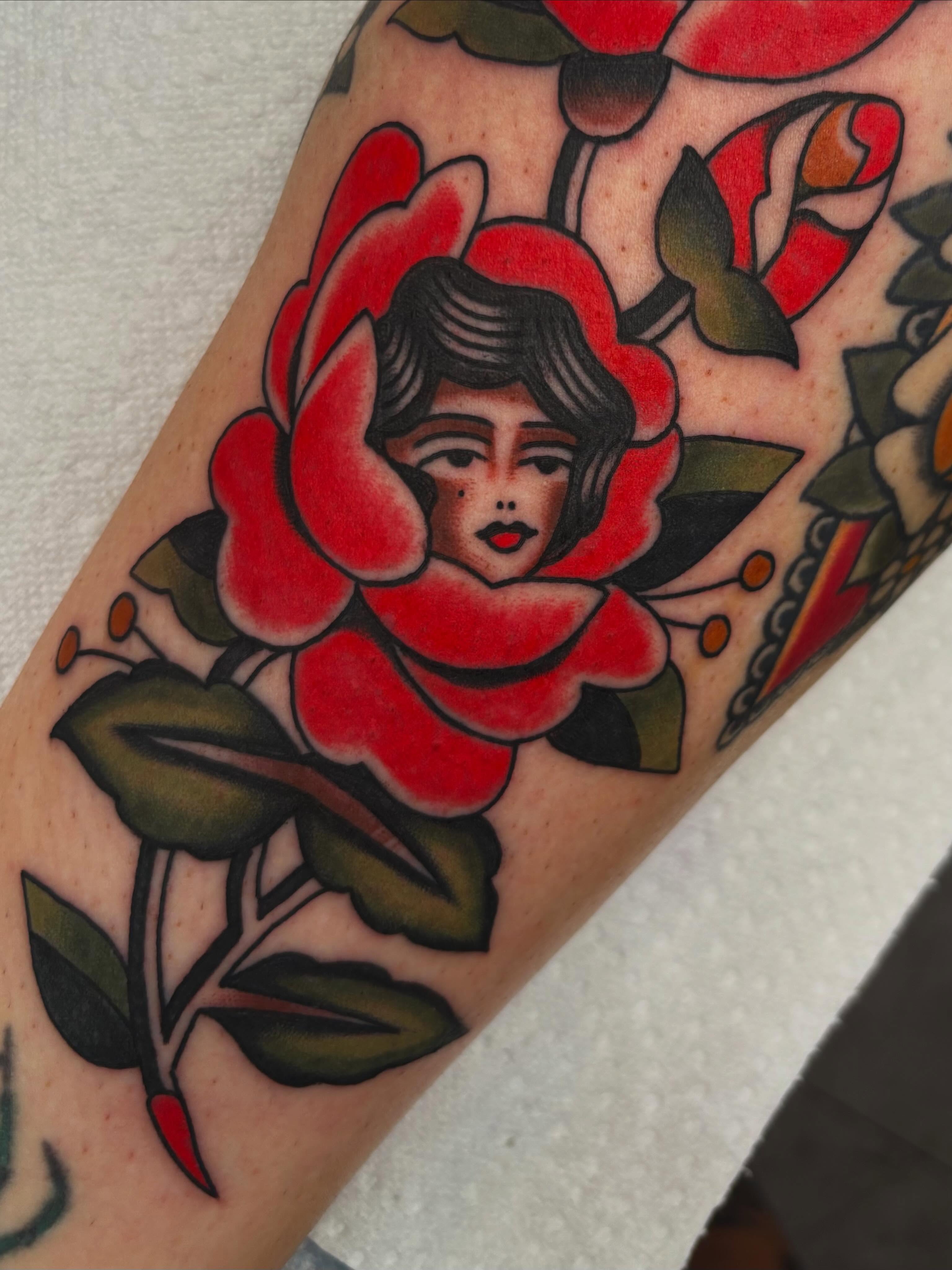 Flower with face American traditional tattoo on the forearm by Claire Anderson