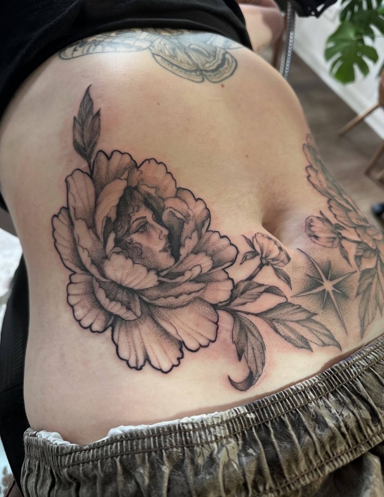 Peony with woman's face realism tattoo on the thigh by Allexis