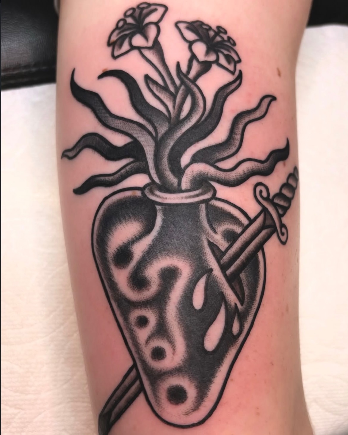 Heart with flowers and sword black and grey tattoo on the forearm by ๐๐๐ฏ๐ข๐ซ