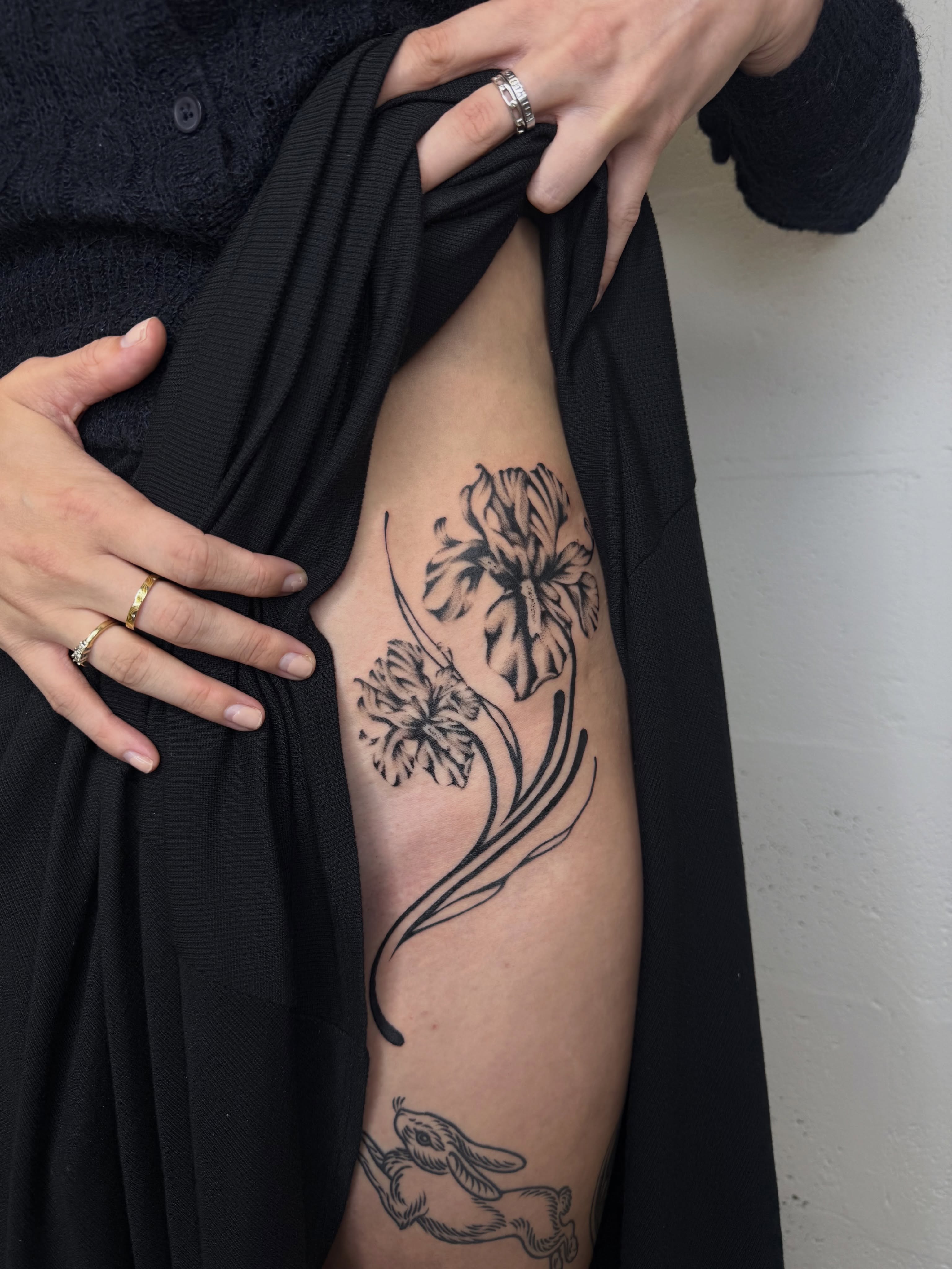 Flowers and rabbit black and grey tattoo on the thigh by Ava Nilou