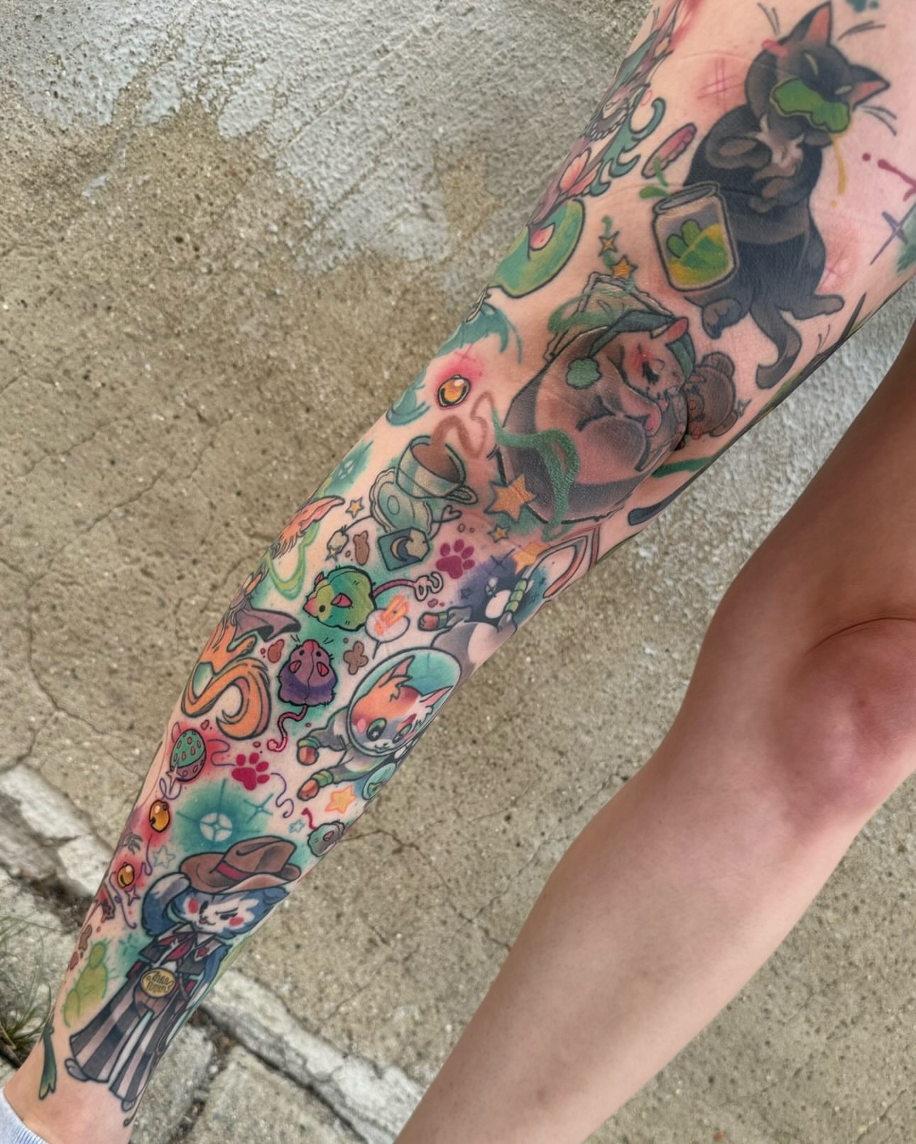 Cat and various characters new school tattoo on the forearm by Taylor Nicoll Chunn