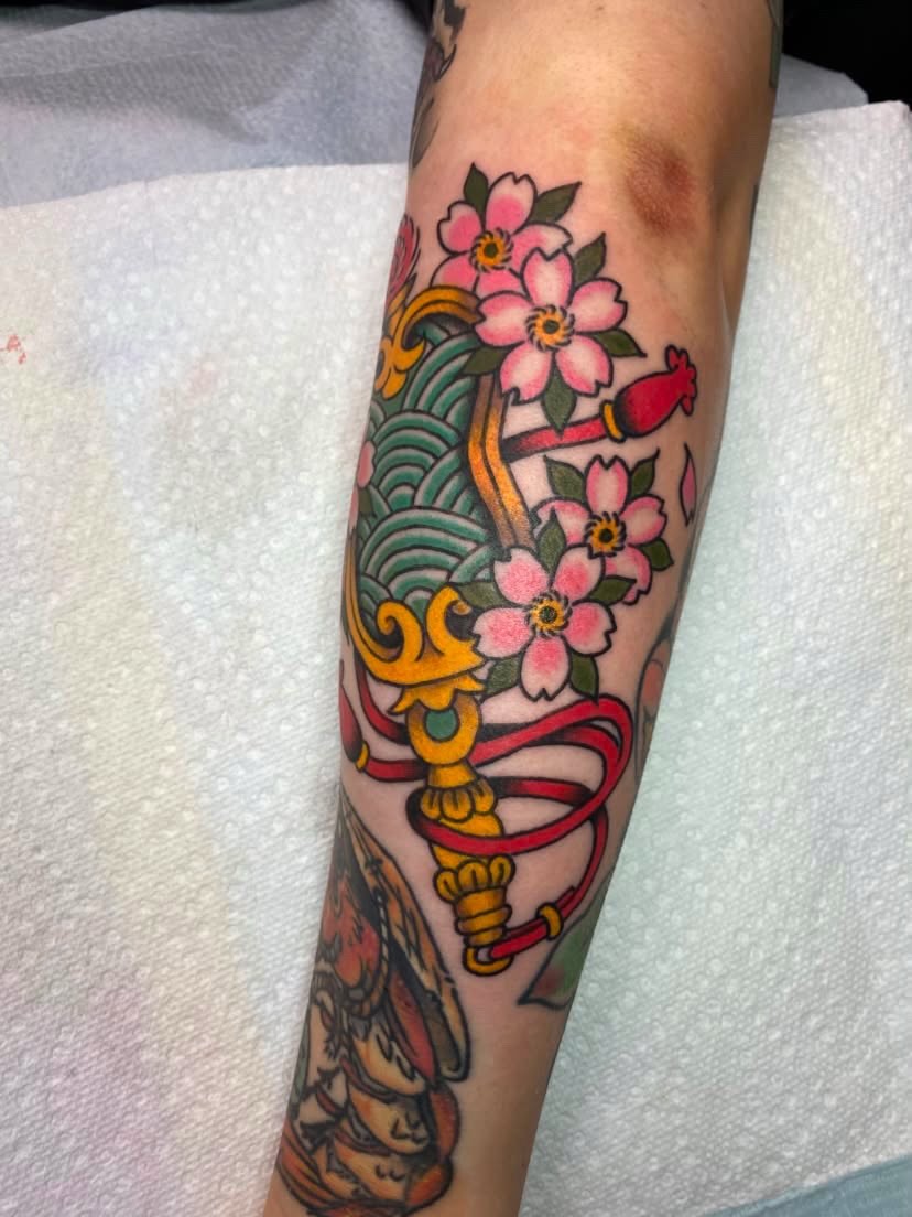 Cherry blossoms and sword American traditional tattoo on the forearm by Natalie Spuhler
