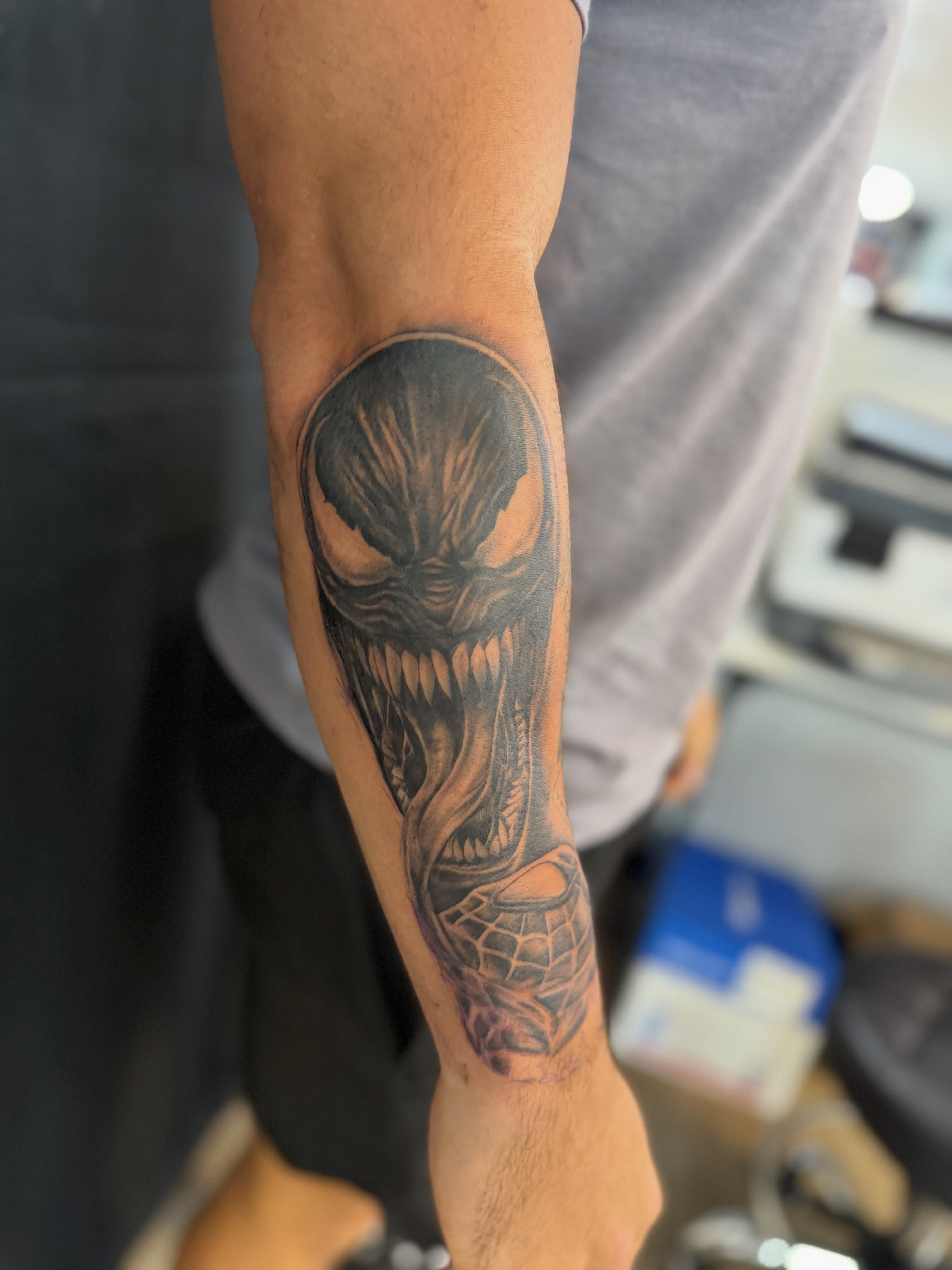 Venom dark realism tattoo on the forearm by Jordan Clifford