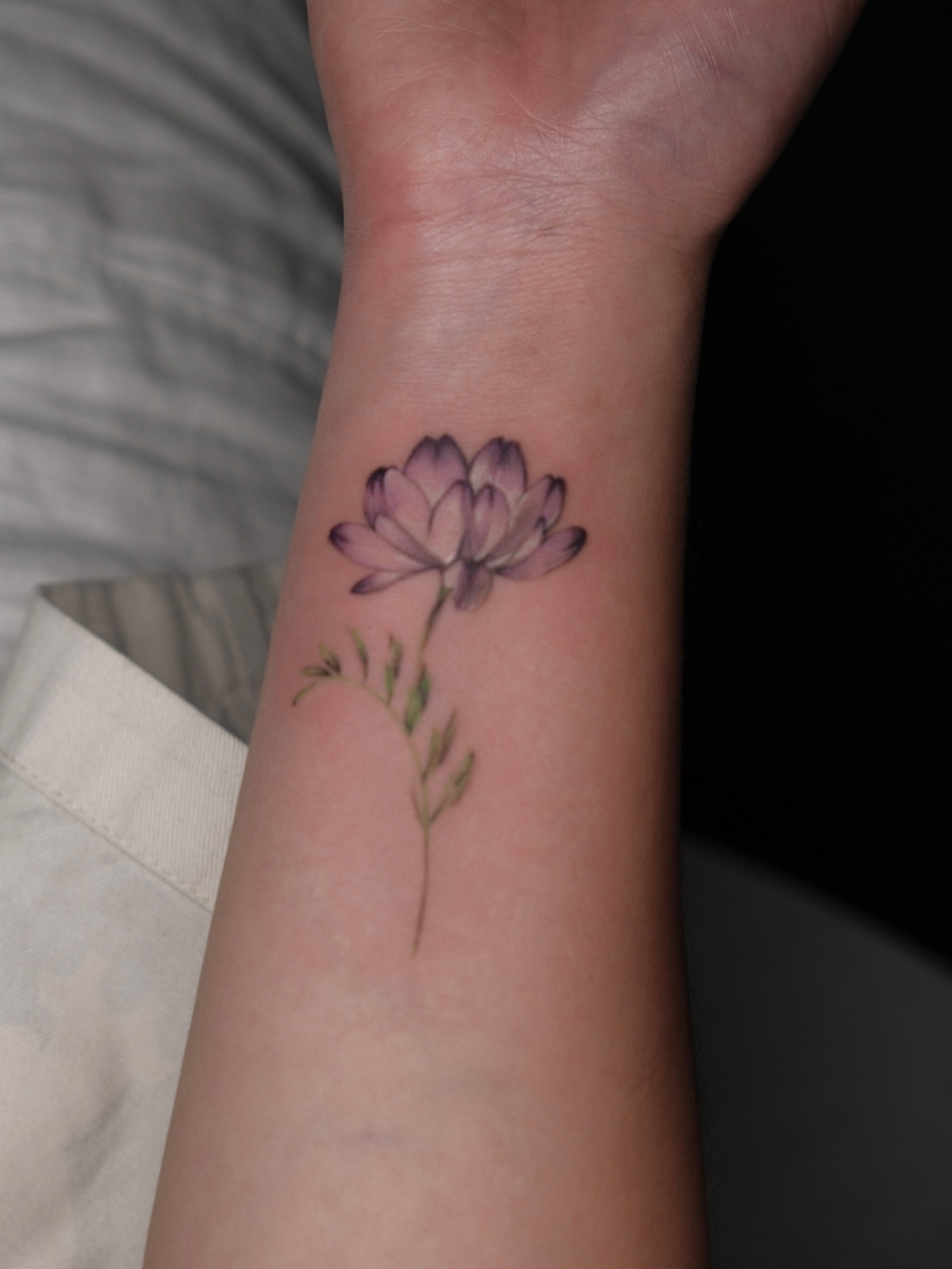 Lotus flower watercolor tattoo on the forearm by Jinz