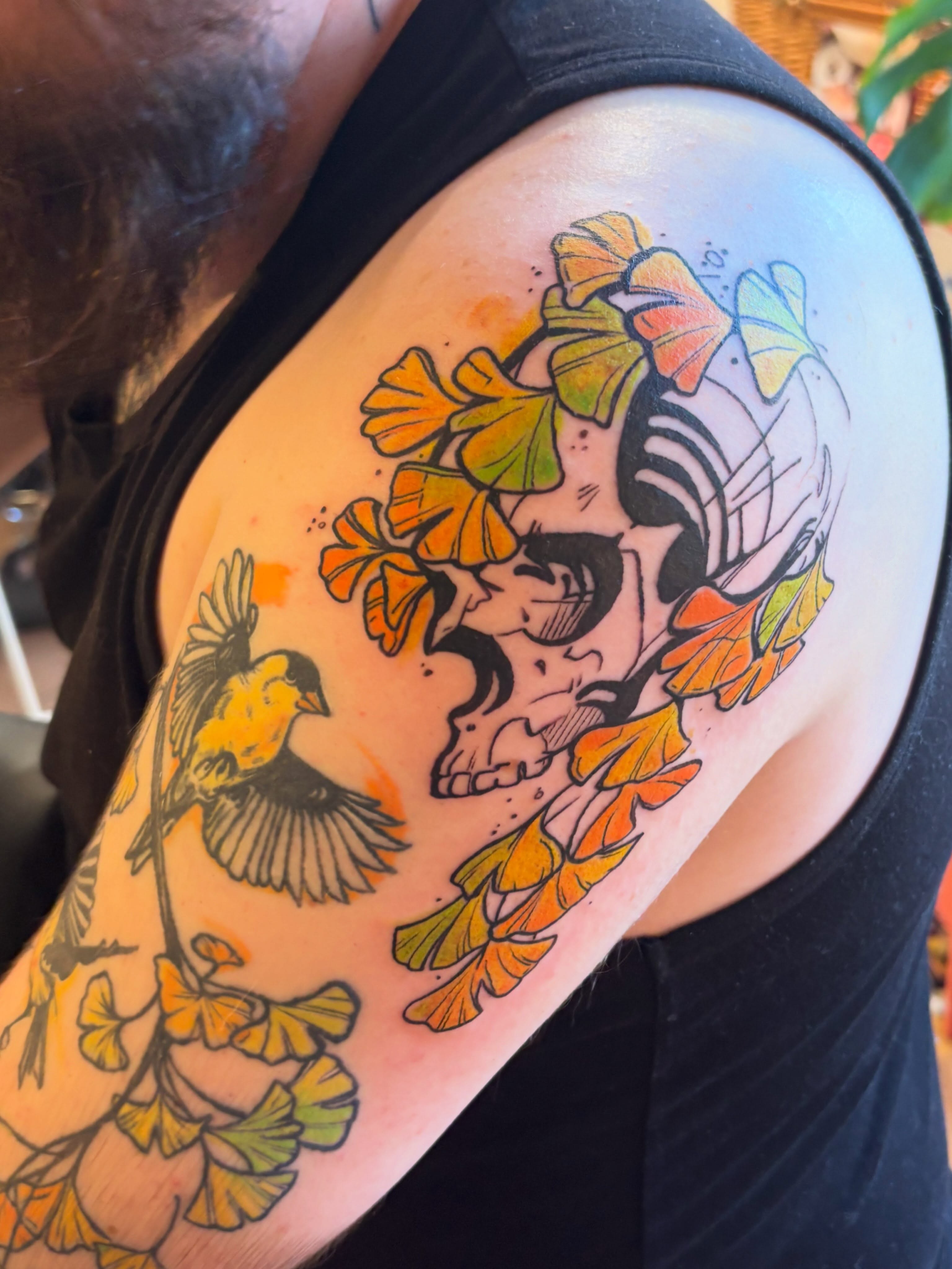 Skull with leaves and bird American traditional tattoo on the shoulder by Zoe Brookes