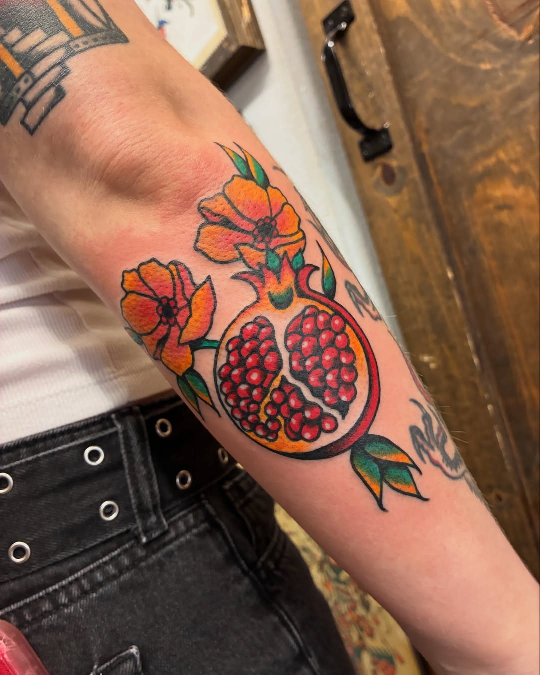 Pomegranate and flower American traditional tattoo on the forearm by Chrissie