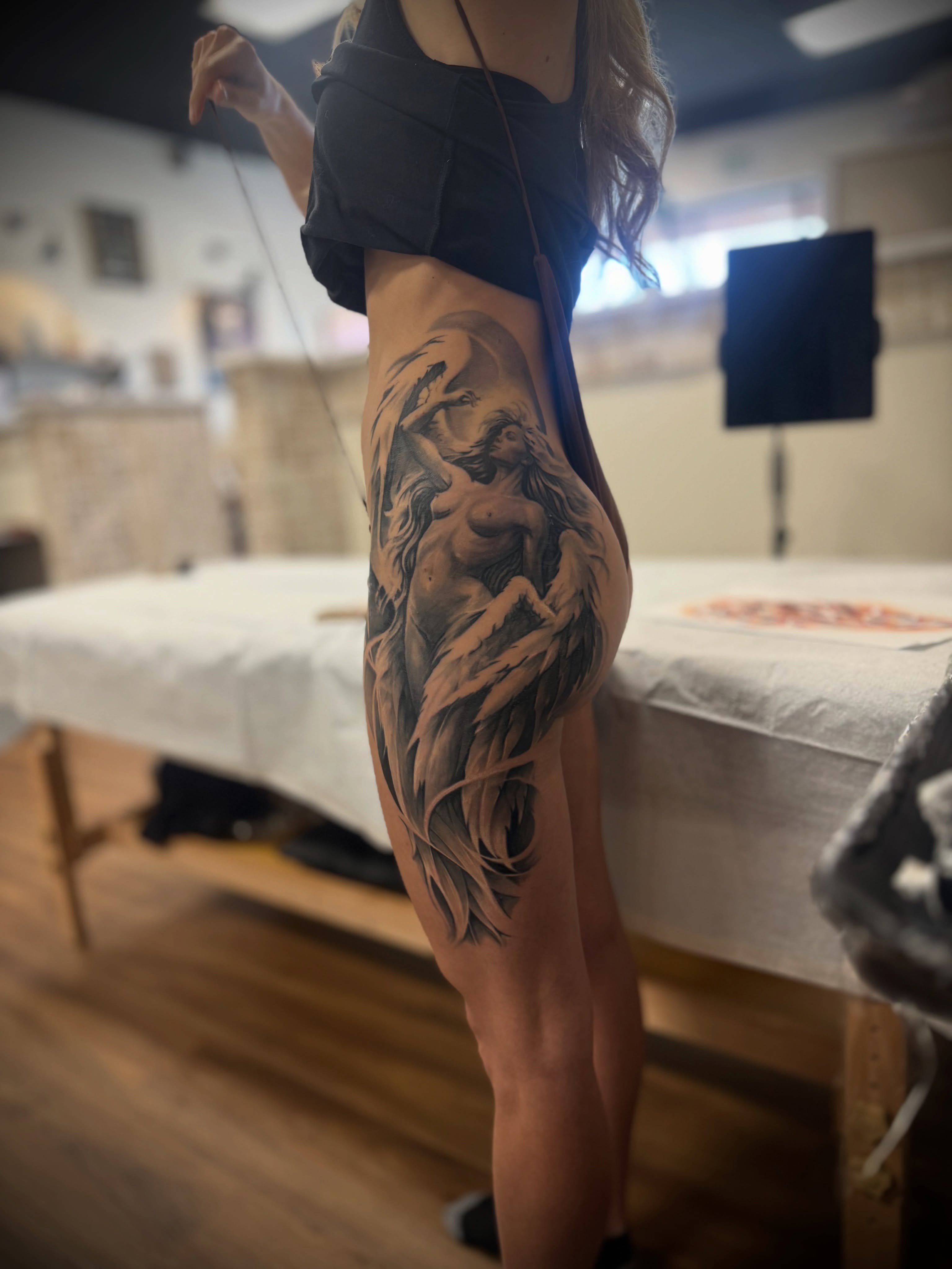 Naked woman black and grey tattoo on the thigh by Julian Olson