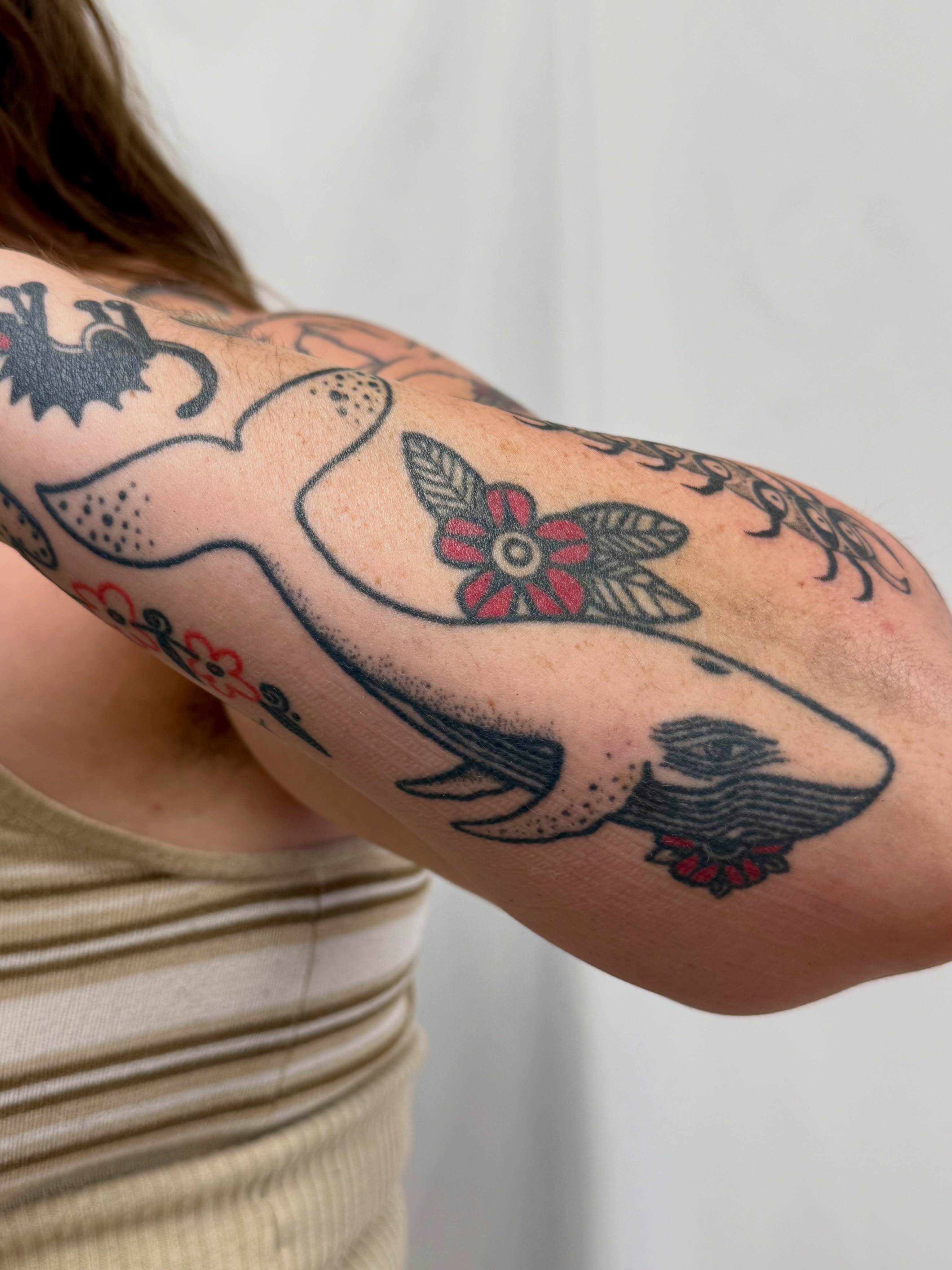 Whale and flower American traditional tattoo on the upper arm by Melia Mariko