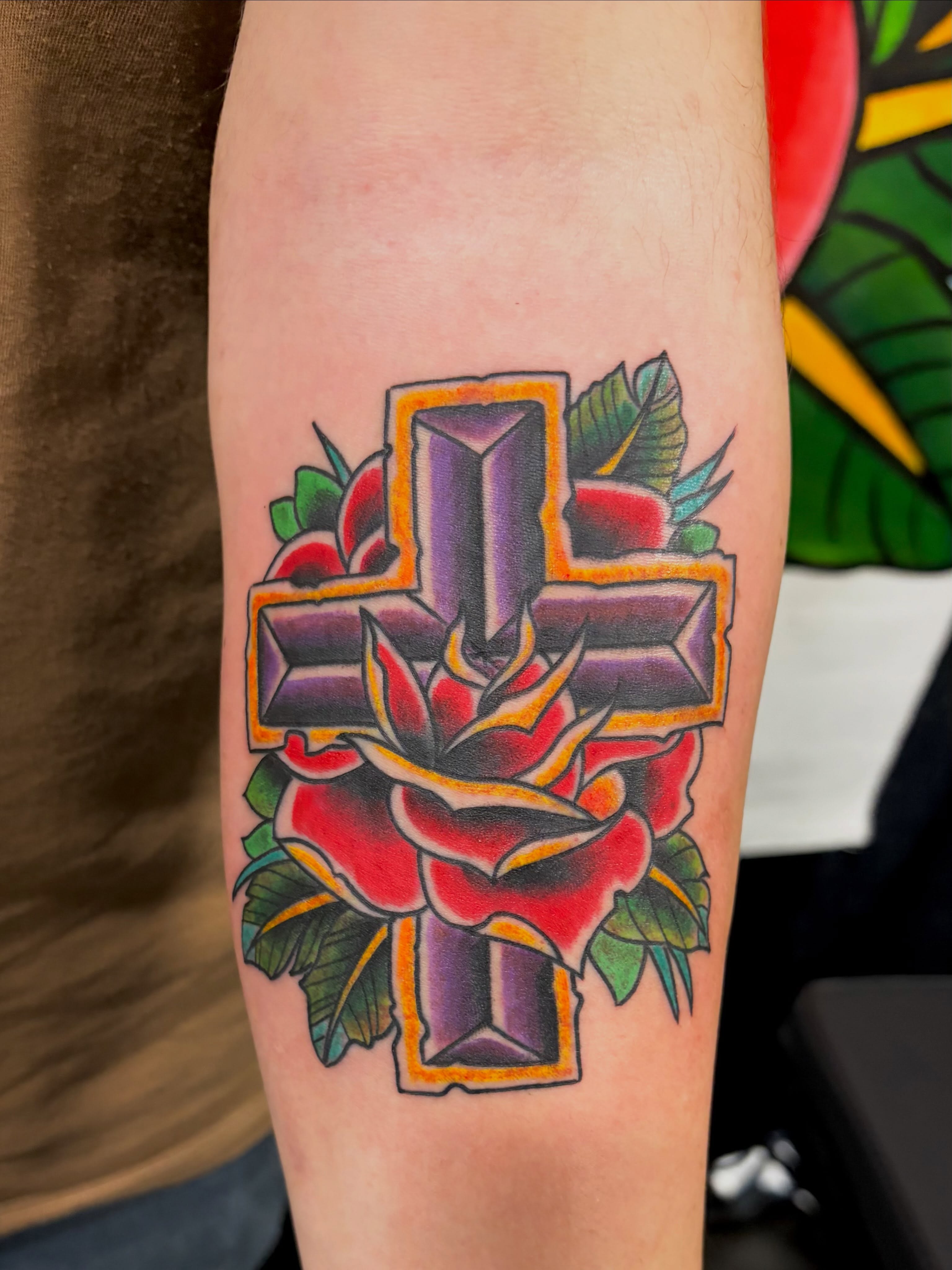 Cross with rose American traditional tattoo on the forearm by @rayscott_tattoo