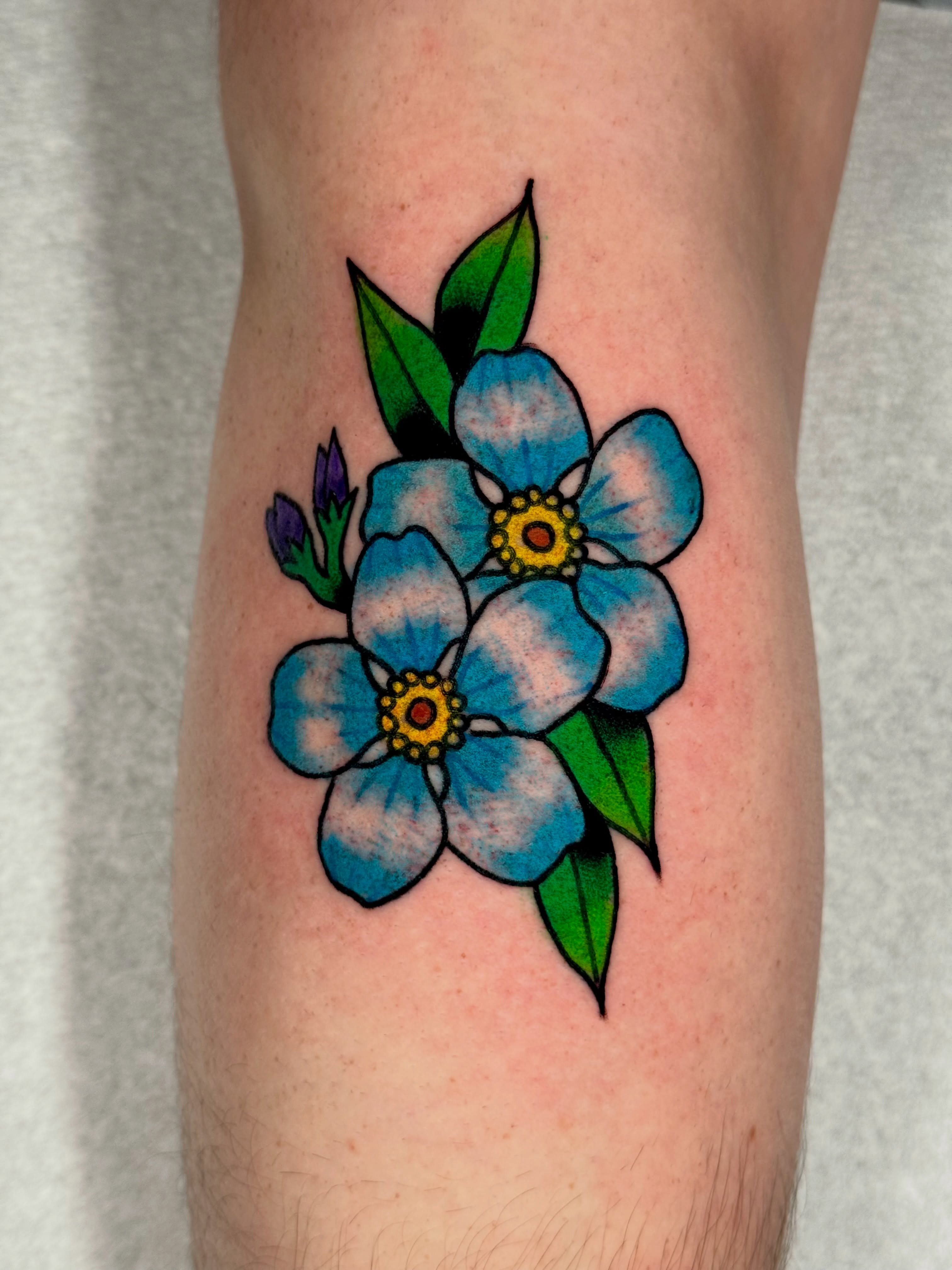 Forget-me-not flowers neo-traditional tattoo on the forearm by Joe Bear Tattooer