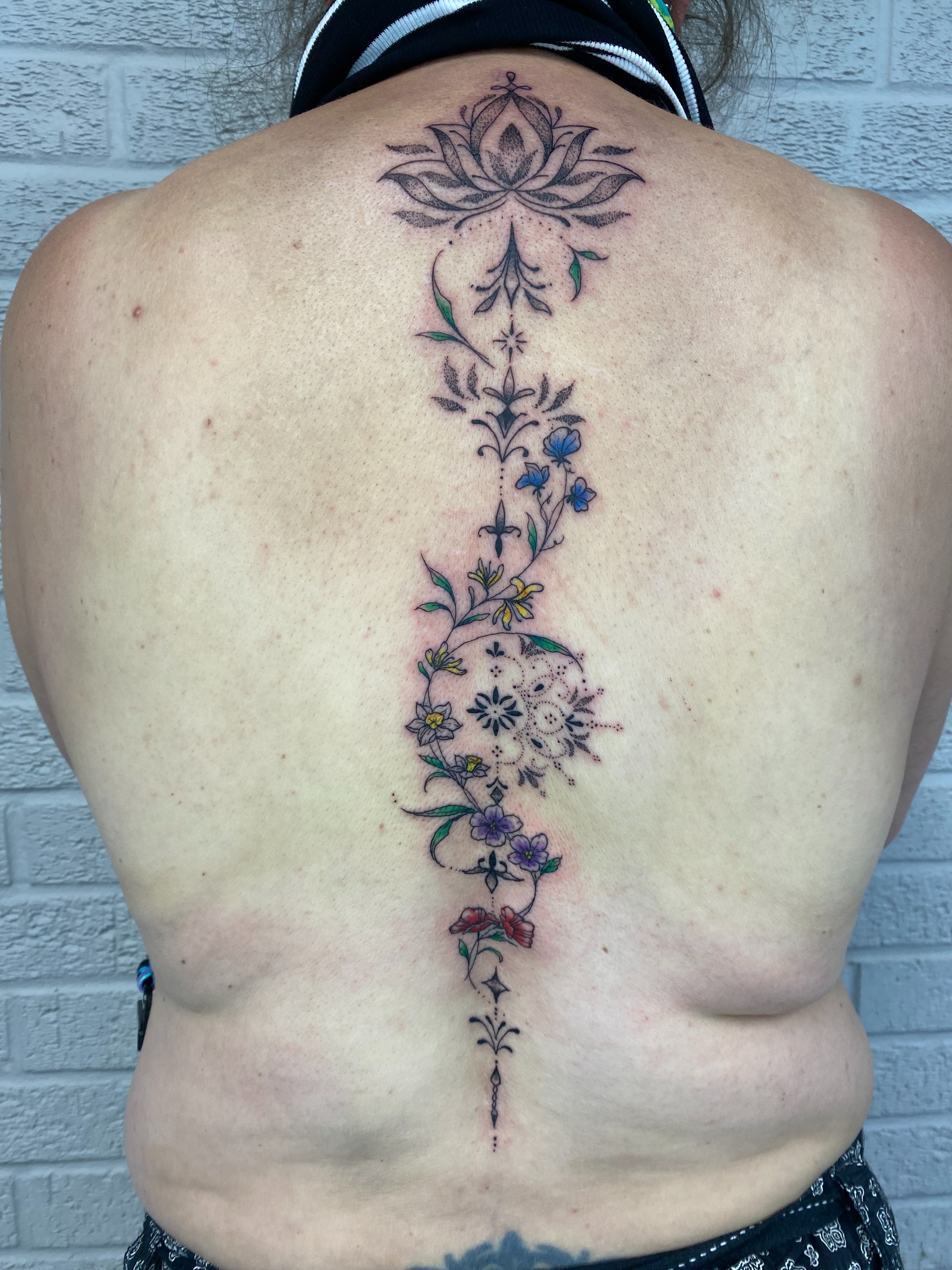 Lotus and floral vine ornamental tattoo on the back by Ellena Reggiani